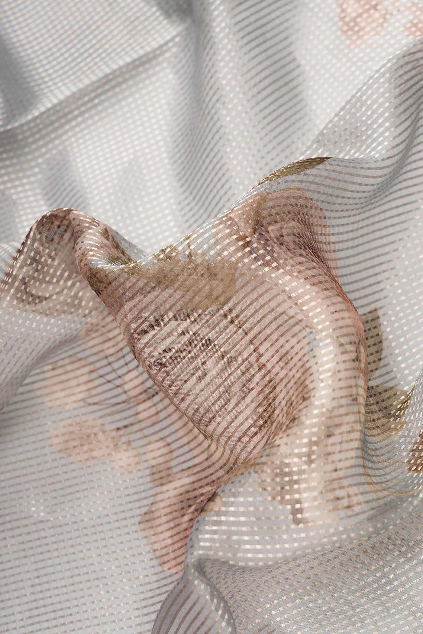 Close up of Grey Dual Tone Organza Silk Saree with Printed design on the body and Without Border.  displaying folds