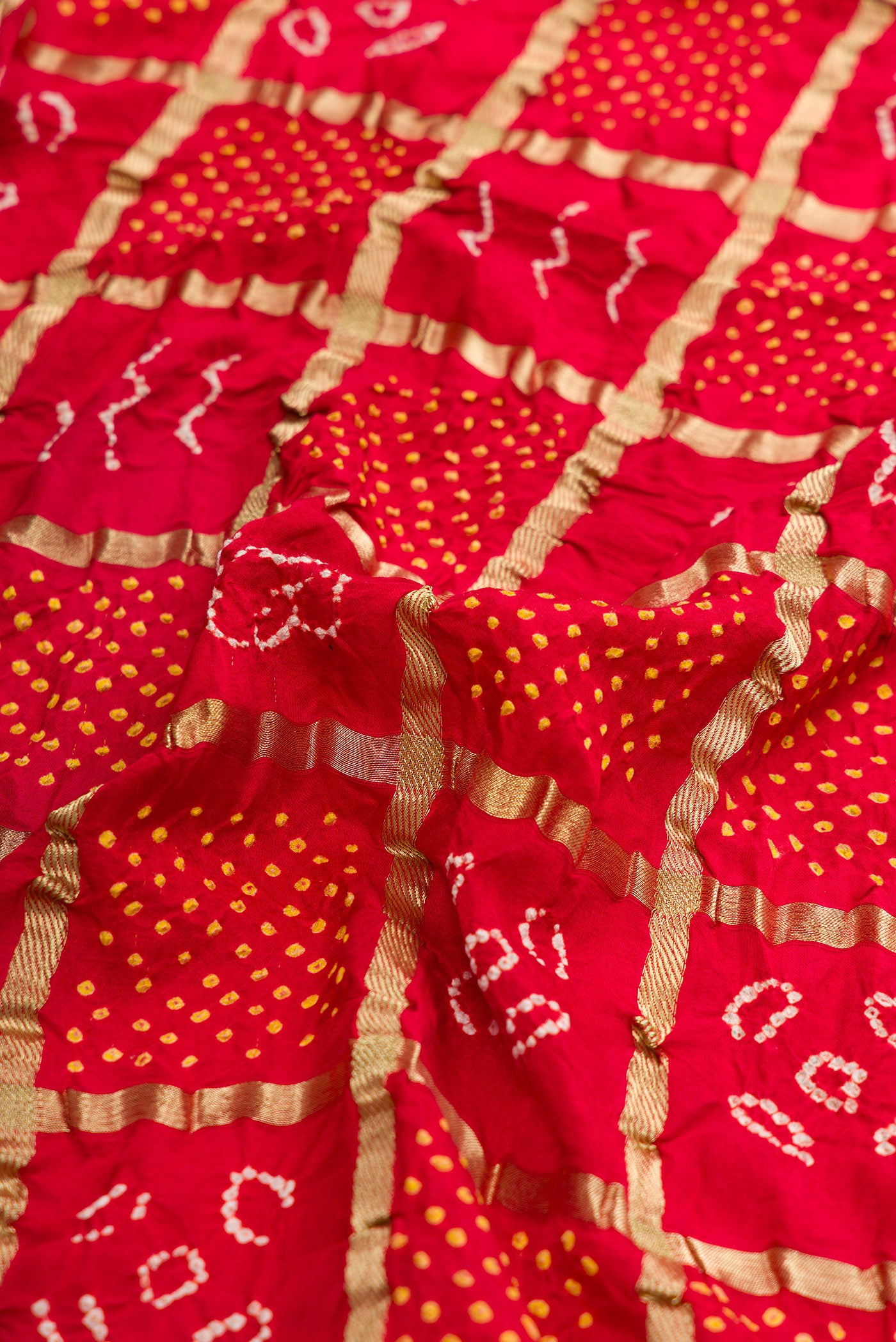 Close up of Red Dual Tone Bandhani Silk Saree with Bandhani Print on the body and Fancy Border.  displaying folds