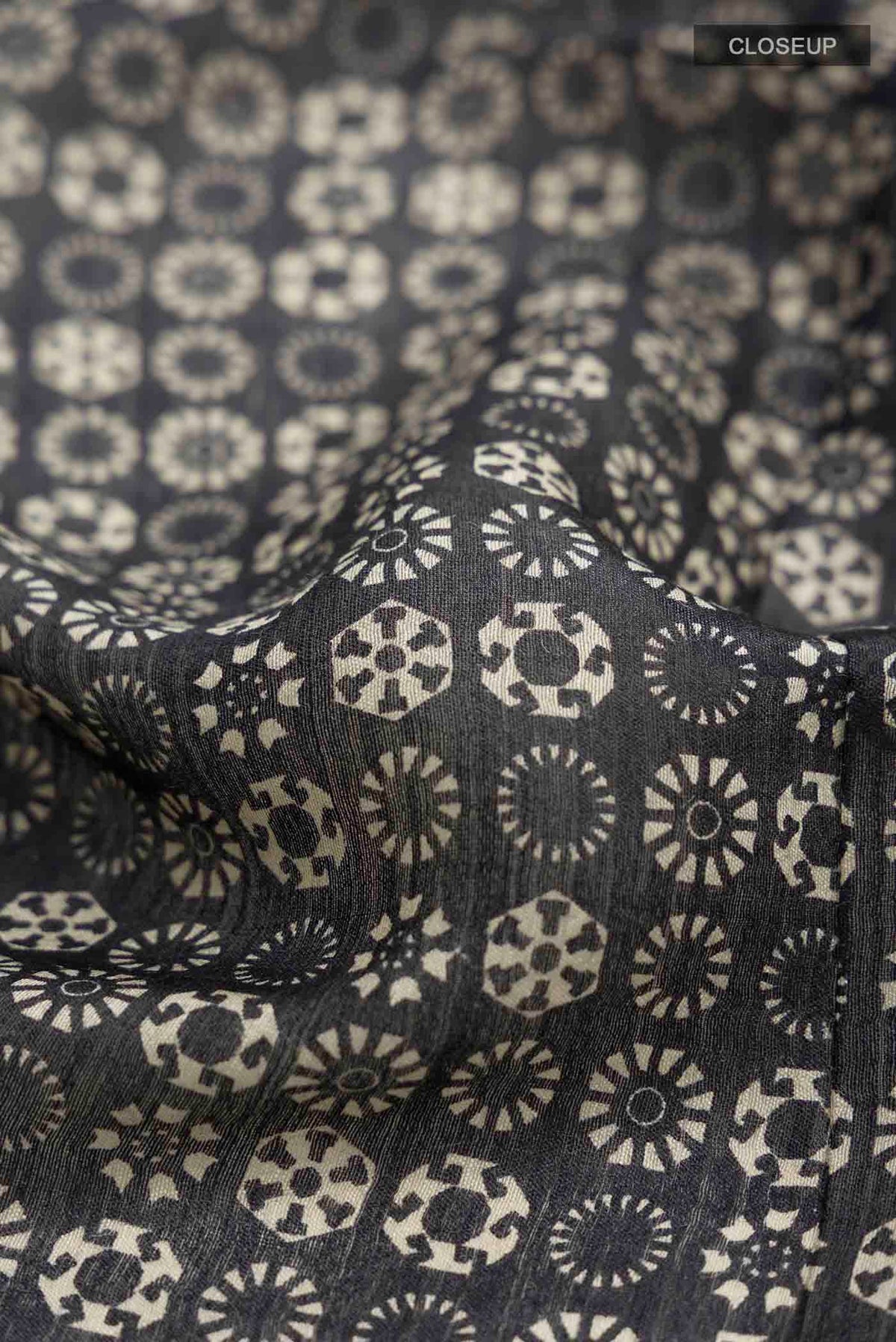 Close up of Black Tussar Silk Saree with Printed design on the body and Zari Border displaying folds