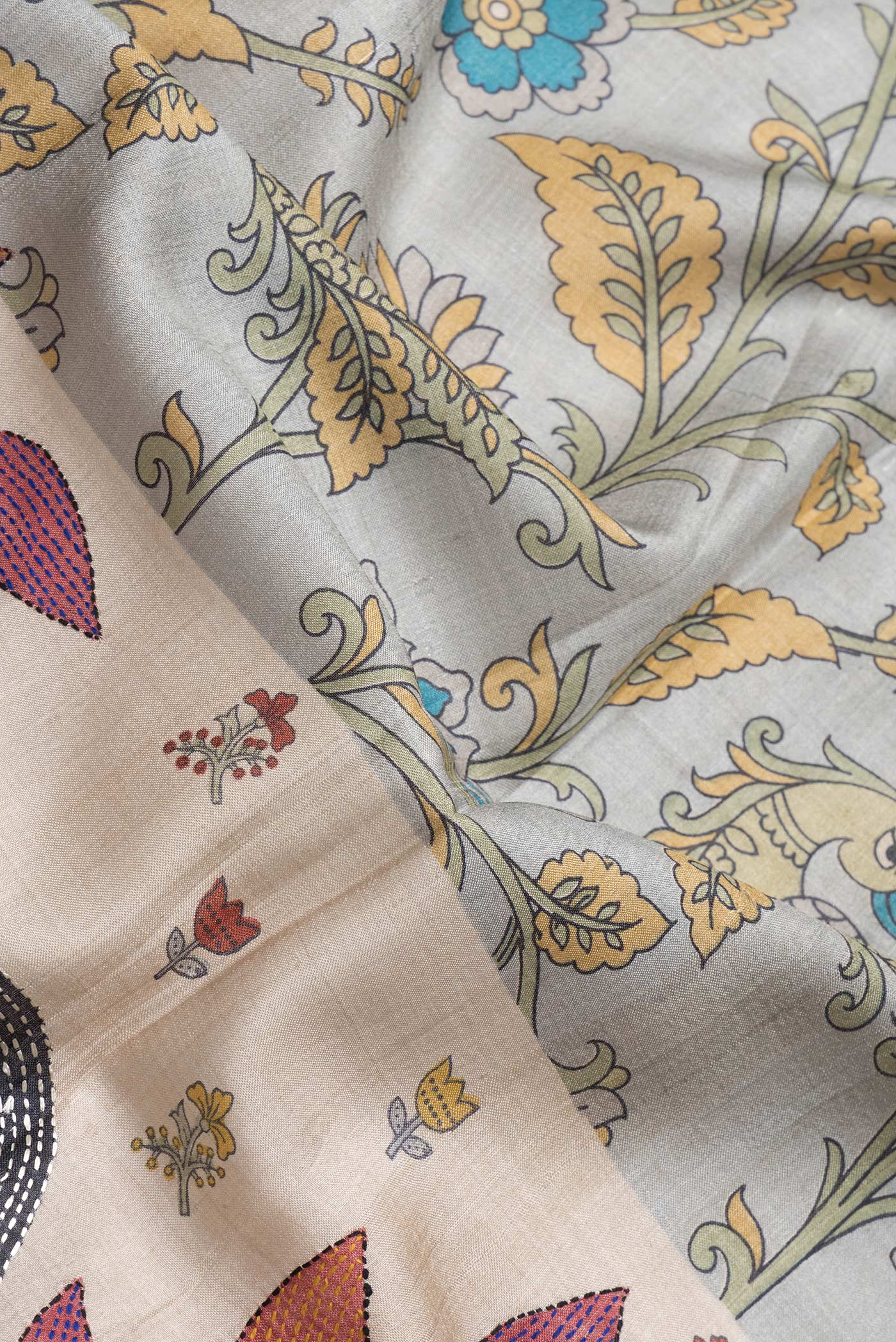 Close up of Grey Dual Tone Tussar Silk Saree with Printed design on the body and Embroidery Border.  displaying folds