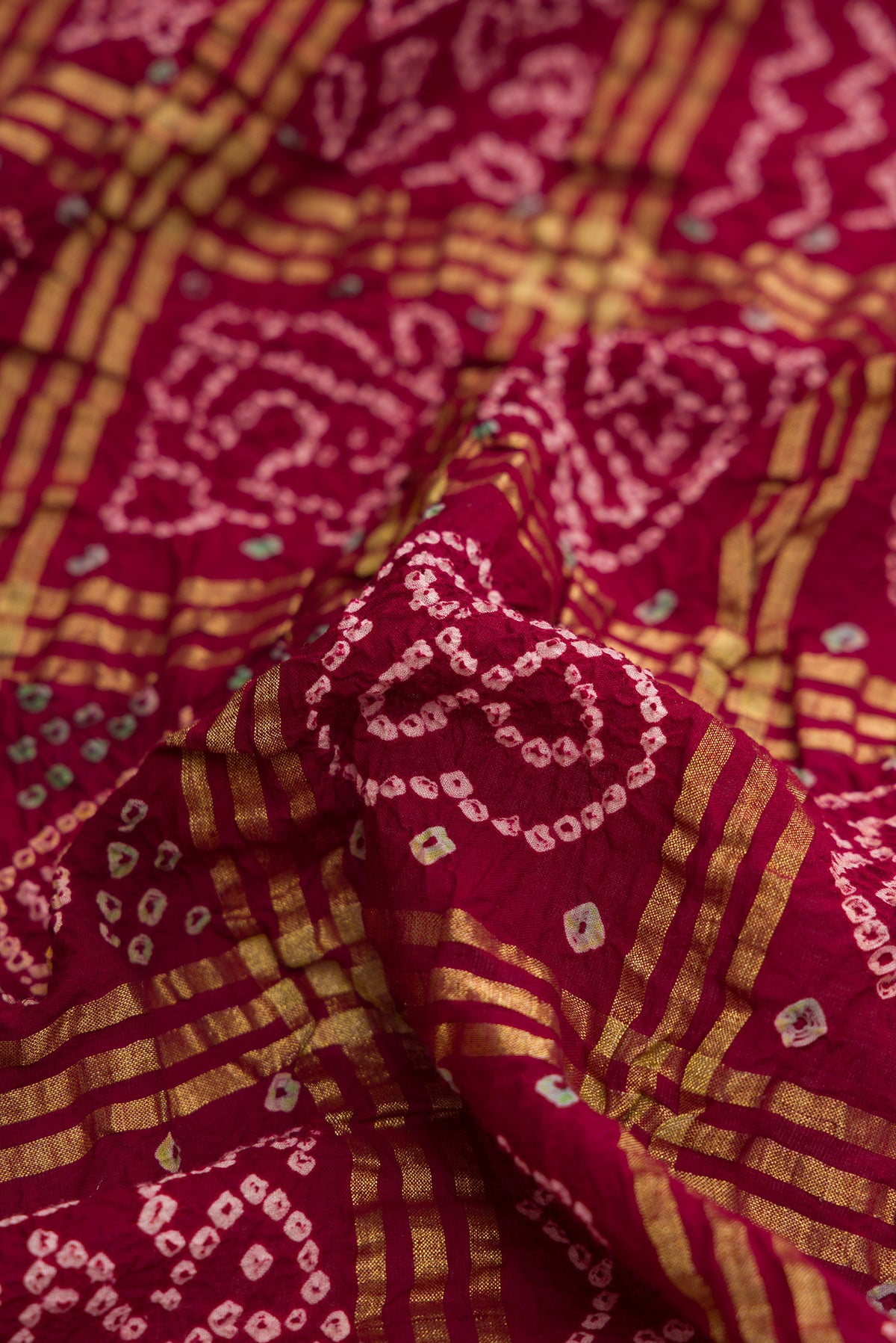 Close up of Maroon Dual Tone Bandhani Silk Saree with Bandhani Print on the body and Paithani Border.  displaying folds