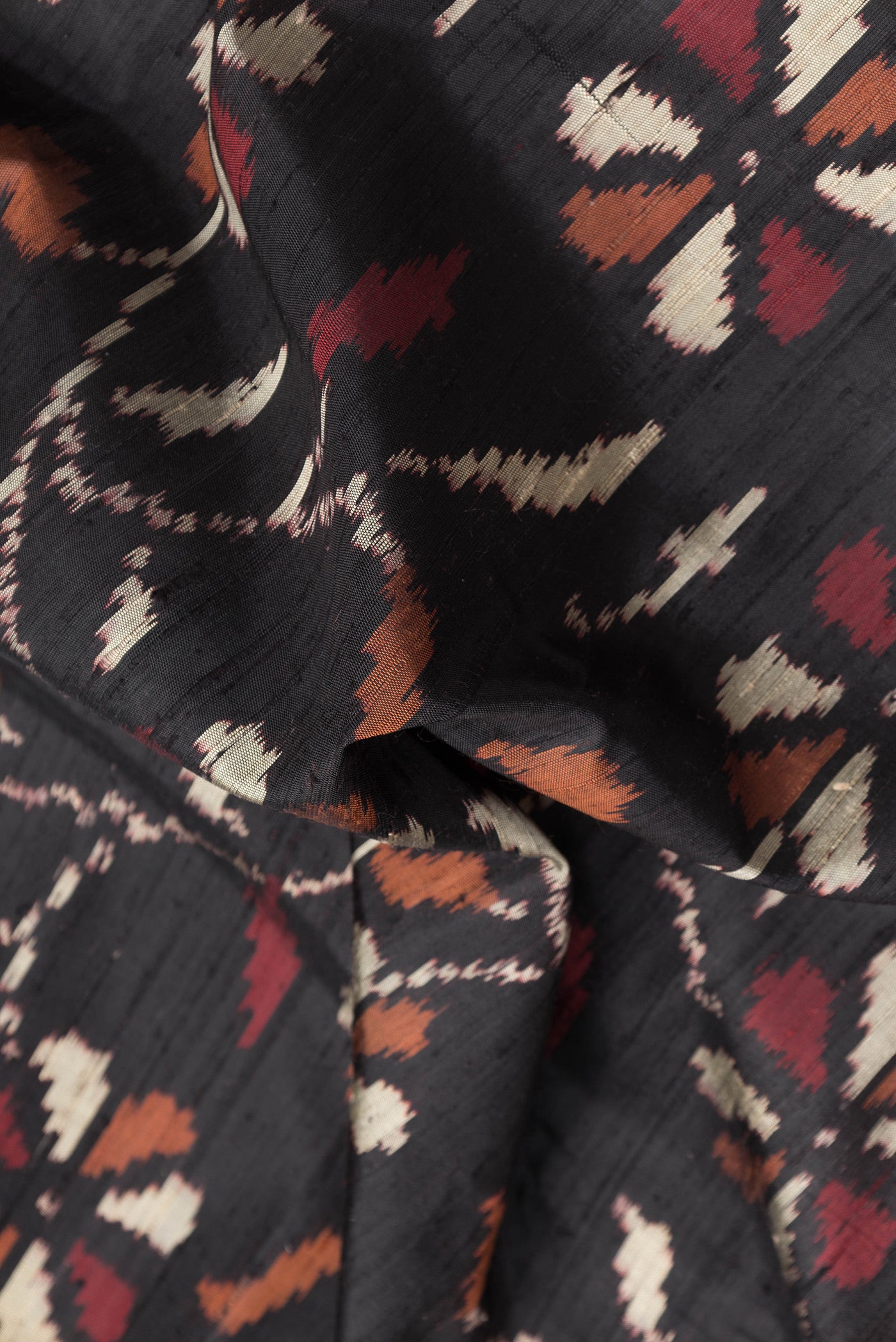 Close up of Black Dual Tone Double Ikat Saree with Ikat Print on the body and Paithani Border.  displaying folds