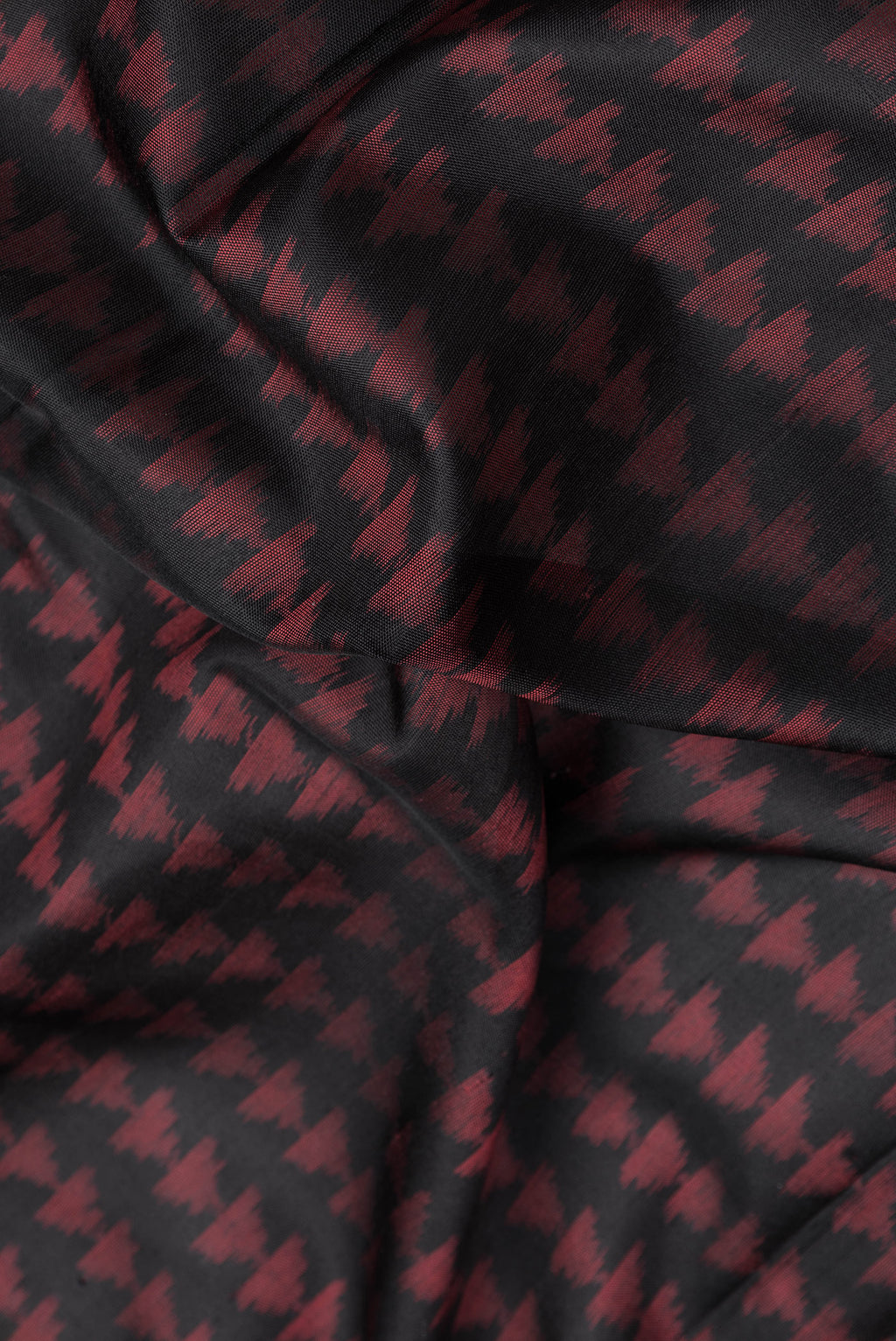 Close up of Black Dual Tone Double Ikat Saree with Ikat Print on the body and Fancy Border.  displaying folds