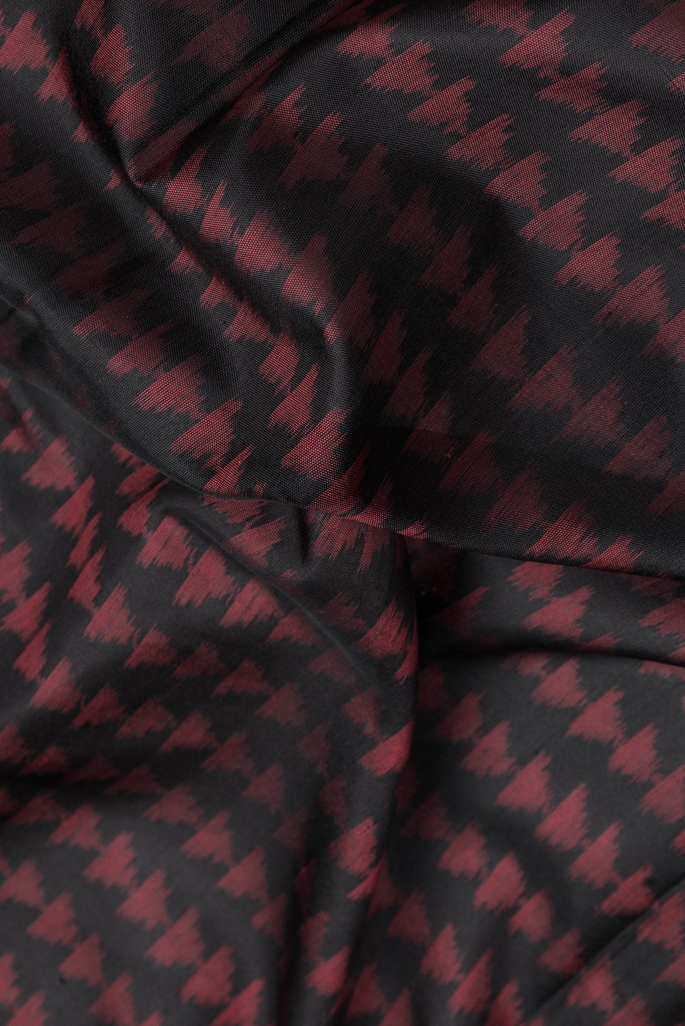 Close up of Black Dual Tone Double Ikat Saree with Ikat Print on the body and Fancy Border.  displaying folds