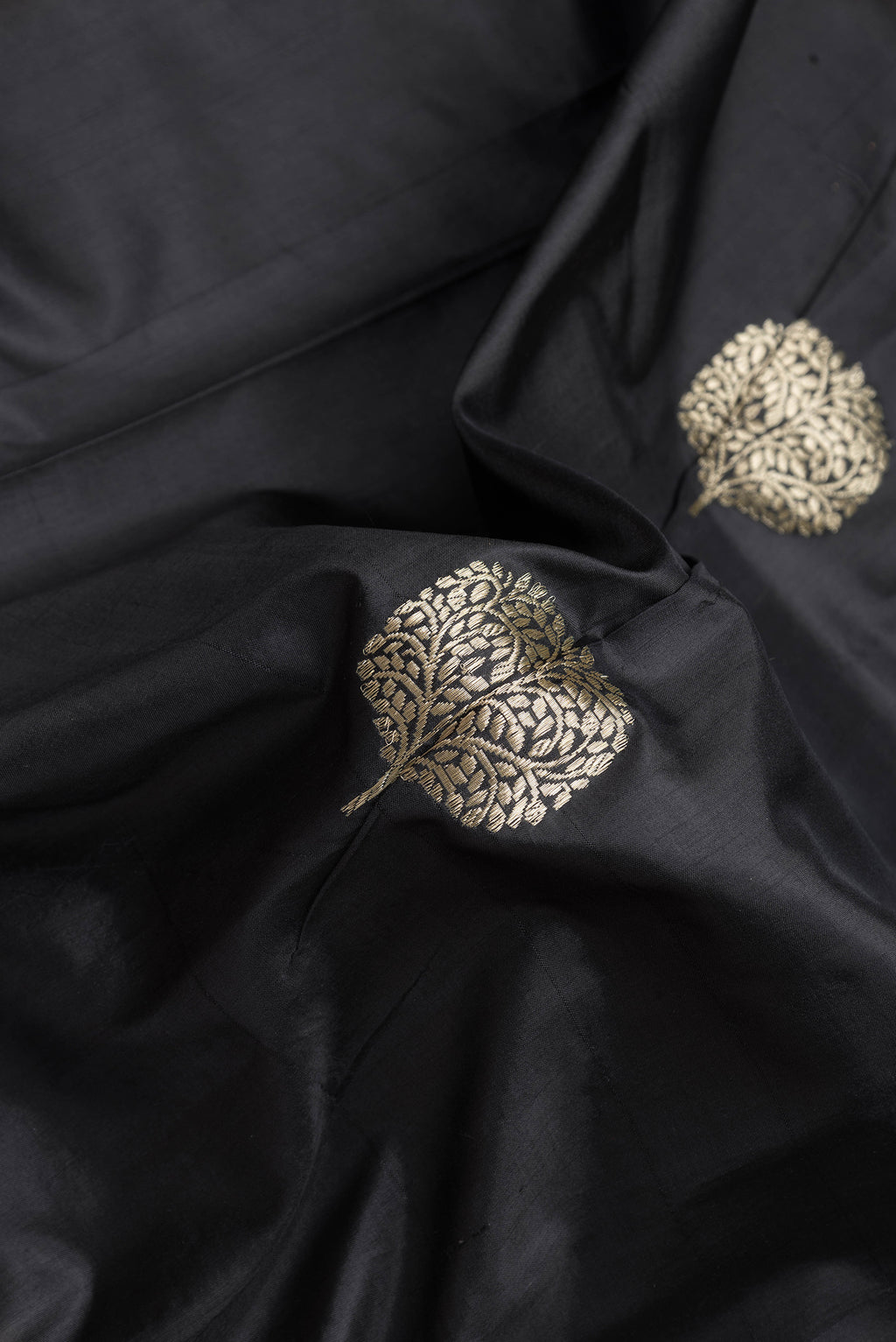 Close up of Black Dual Tone Banarasi Silk Saree with Zari Butta on the body and Paithani Border.  displaying folds