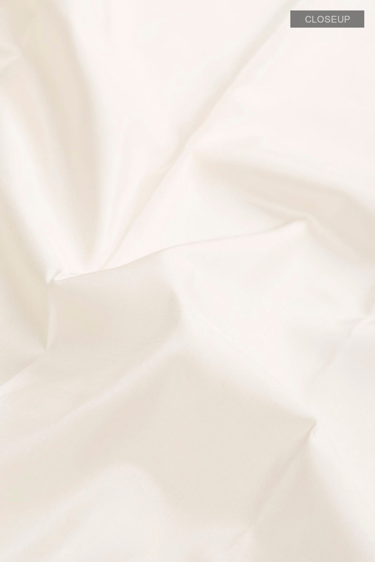 Close up of White Kanchipuram Silk Saree with Plain Body and Zari Border displaying folds