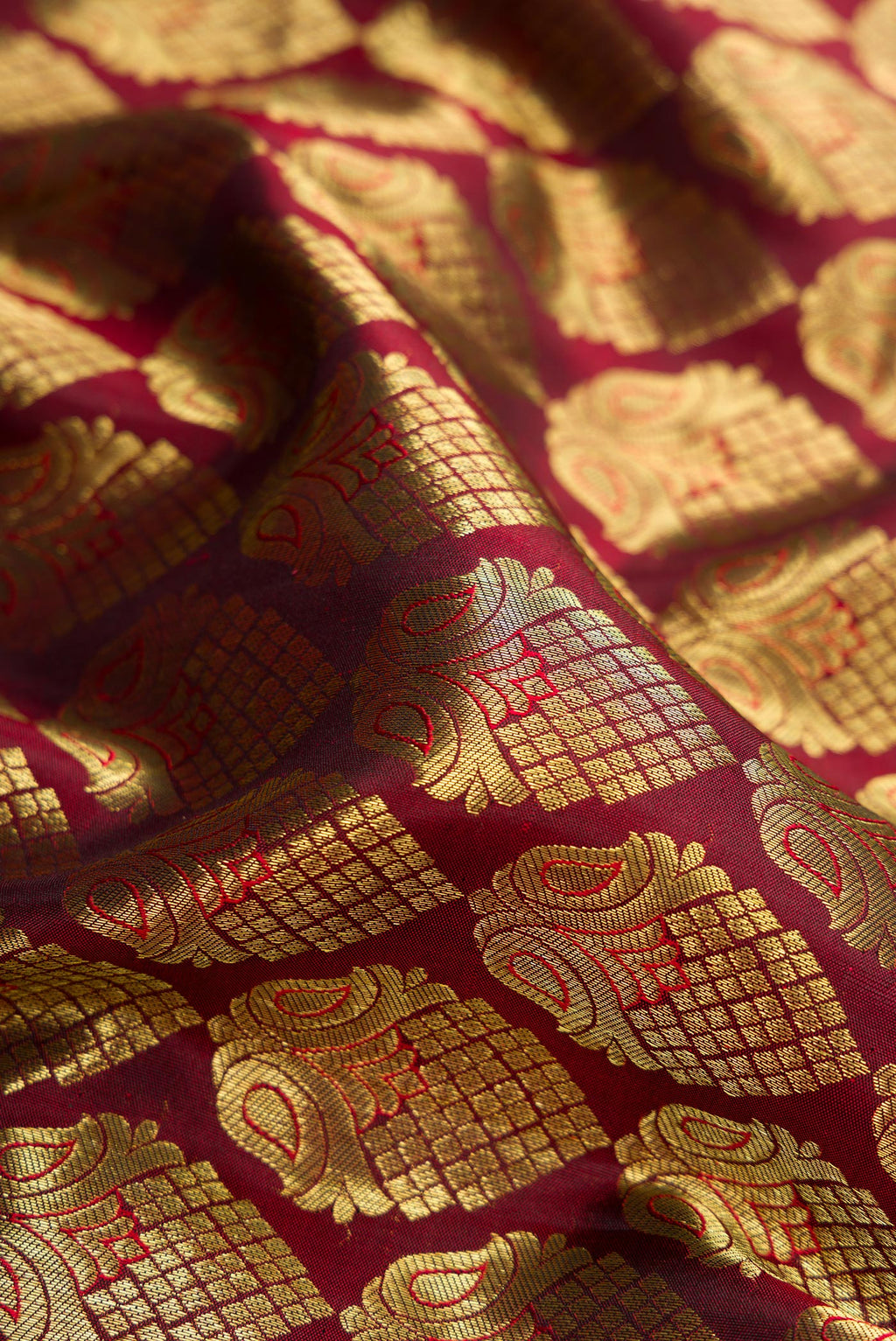Close up of Maroon Dual Tone Kanjivaram Silk Saree with Zari Brocade on the body and Zari Border.  displaying folds