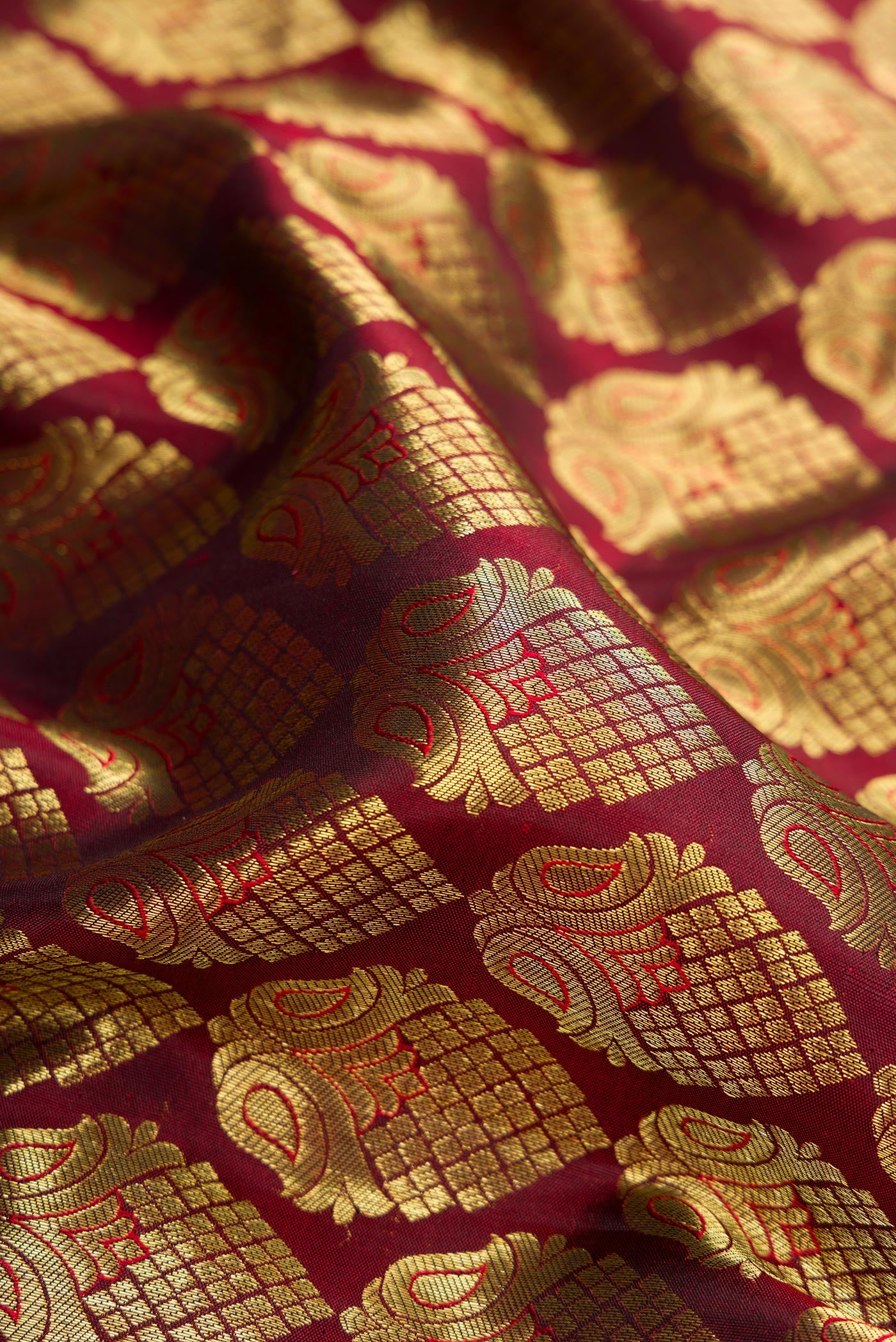Close up of Maroon Dual Tone Kanjivaram Silk Saree with Zari Brocade on the body and Zari Border.  displaying folds