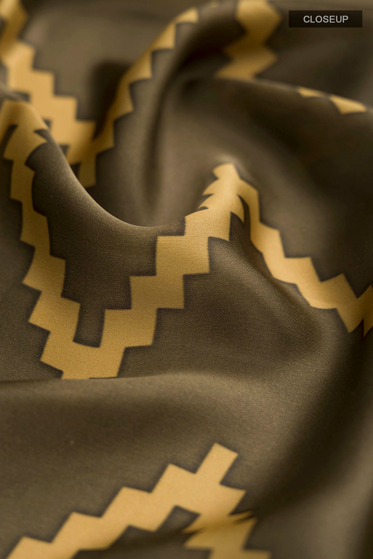 Close up of Green Satin Silk Saree with Abstract Print on the body and Printed Border displaying folds