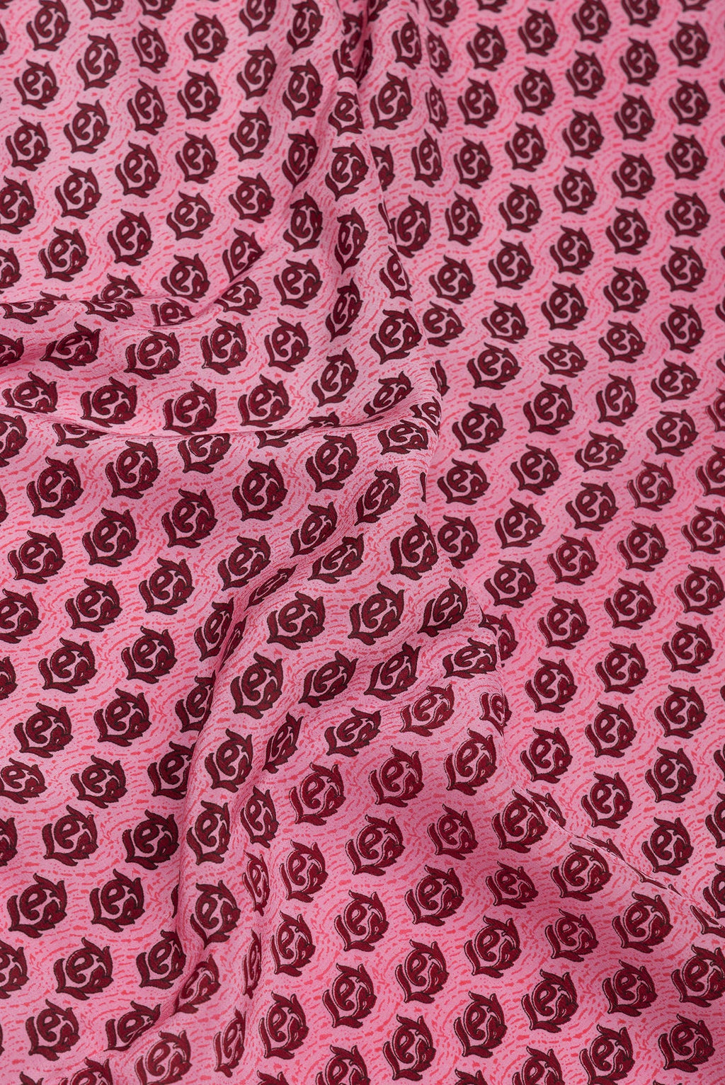 Close up of Pink Crepe Saree with Printed design on the body and Printed Border.  displaying folds