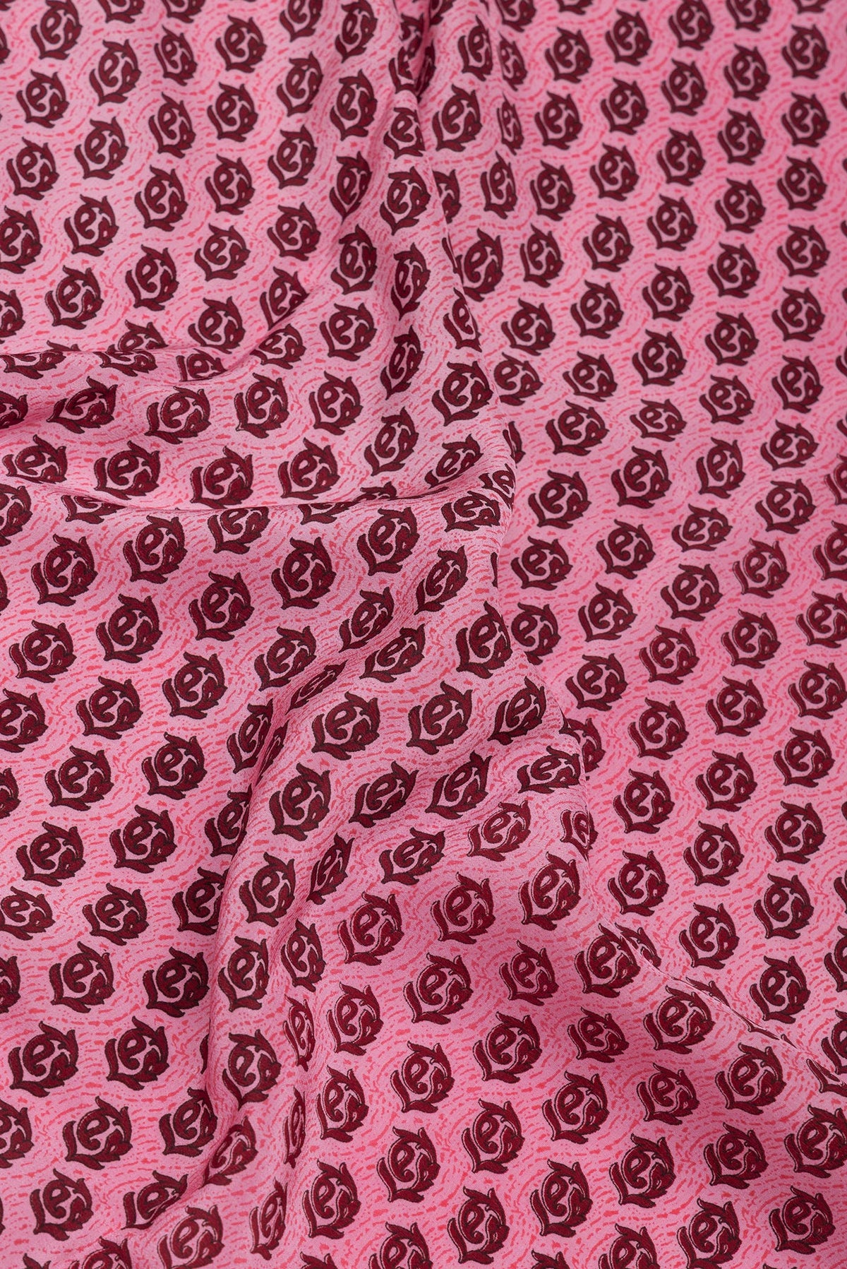 Close up of Pink Crepe Saree with Printed design on the body and Printed Border.  displaying folds
