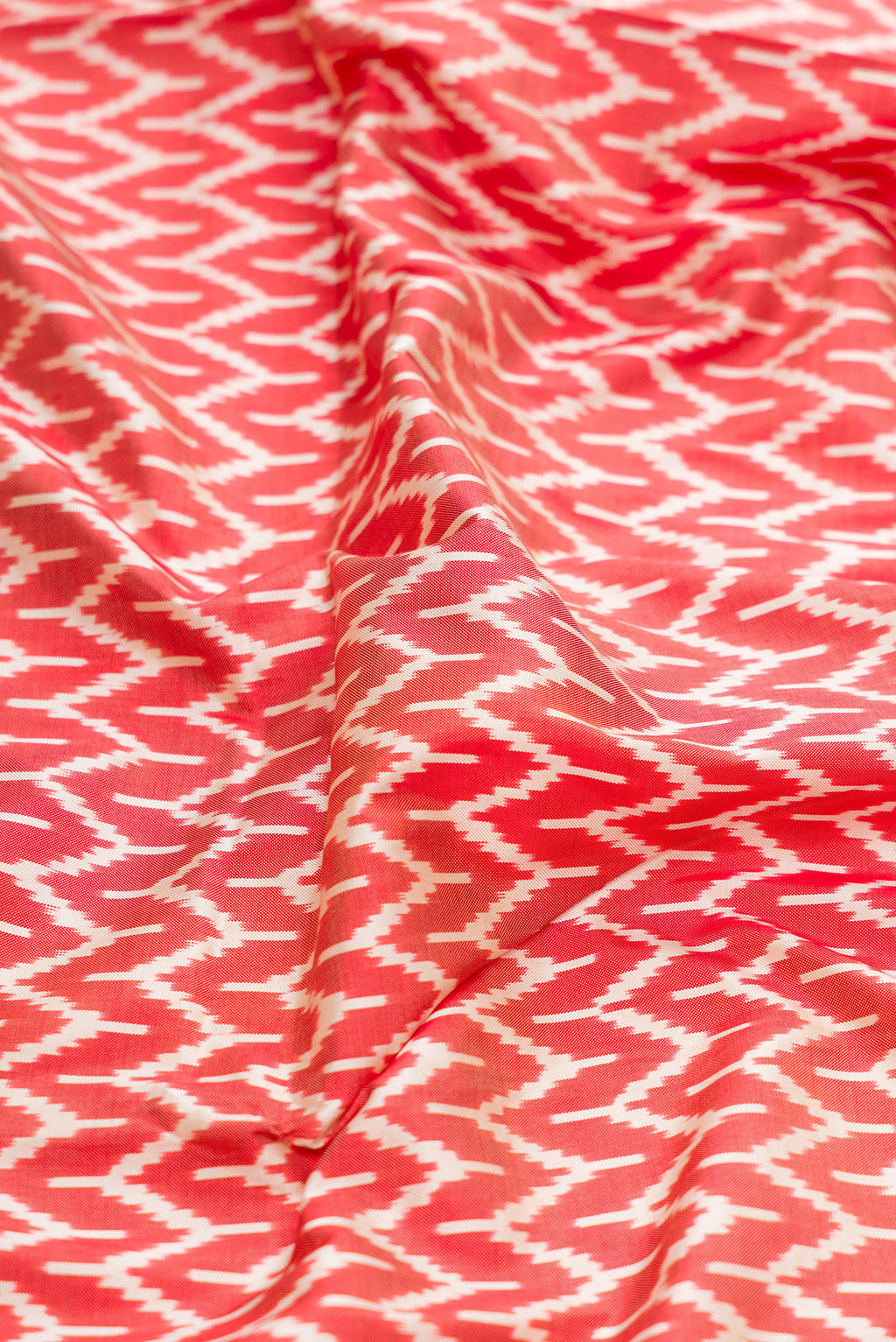 Close up of Maroon Dual Tone Double Ikat Saree with Ikat Print on the body and Zari Border.  displaying folds