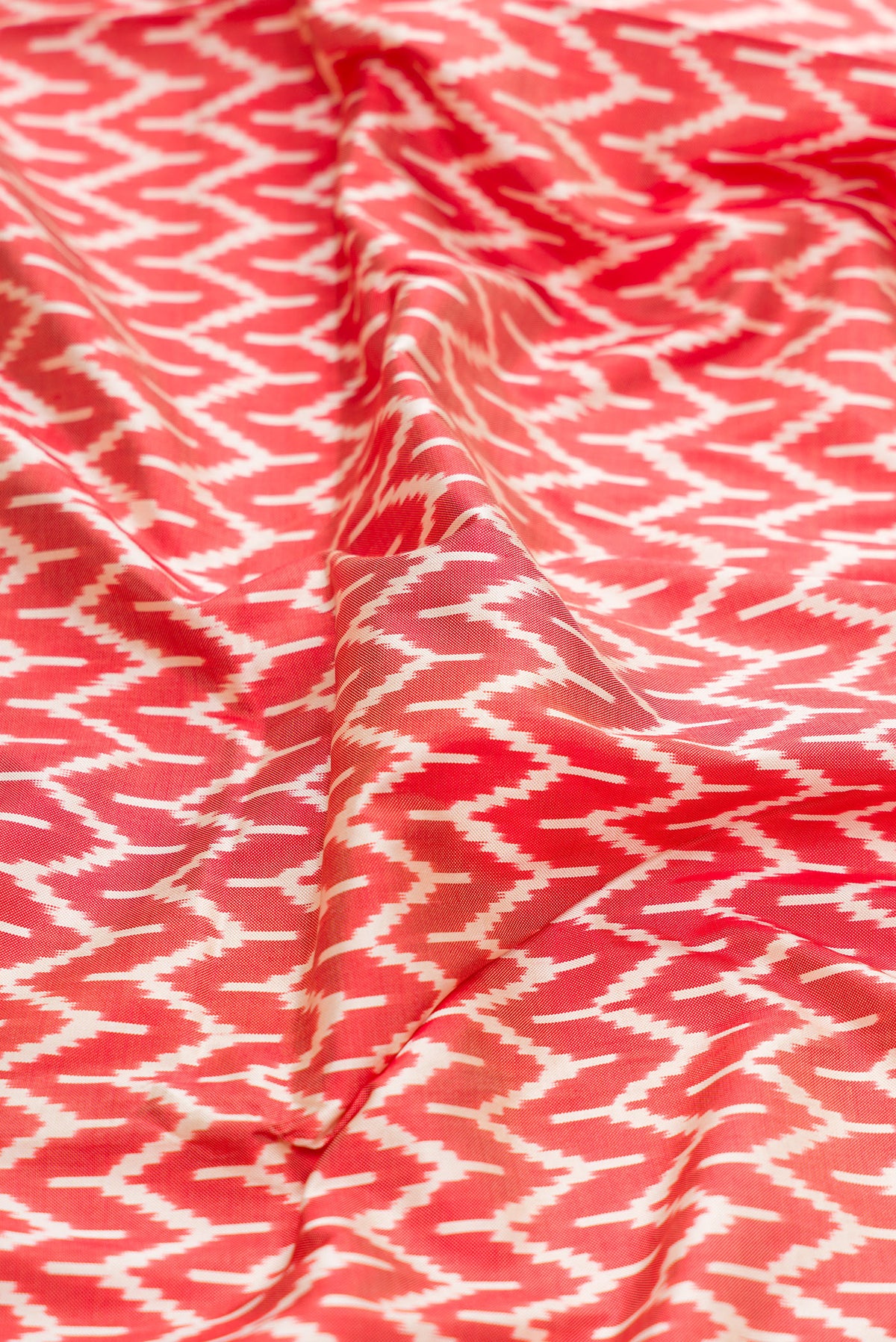 Close up of Maroon Dual Tone Double Ikat Saree with Ikat Print on the body and Zari Border.  displaying folds