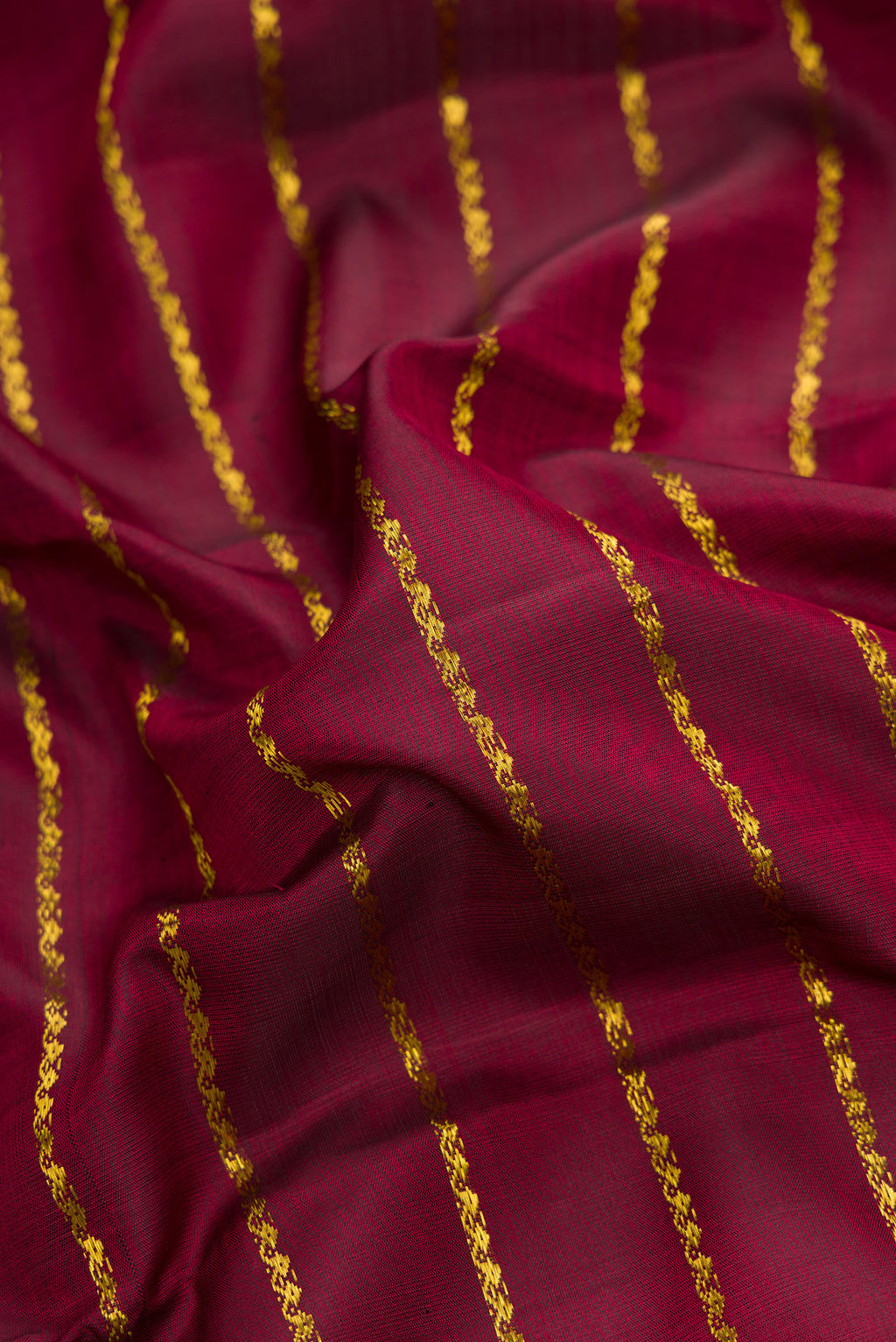 Close up of Maroon Dual Tone Kanchipuram Silk Saree with Stripes on the body and Checks Border.  displaying folds