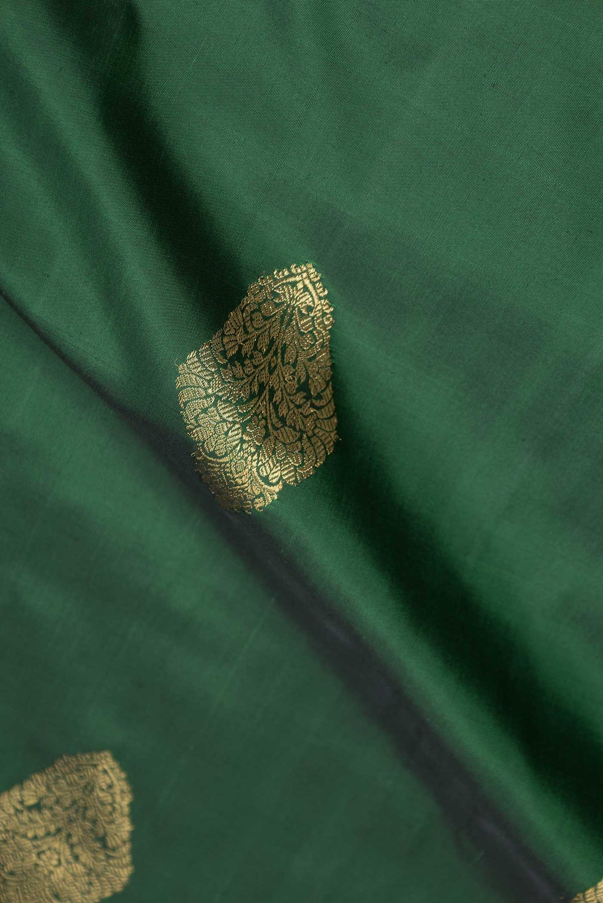 Close up of Pure Silk Pure Zari Bottle Green Dual Tone Kanchipuram Saree with Zari Butta on the body and Zari Border displaying folds