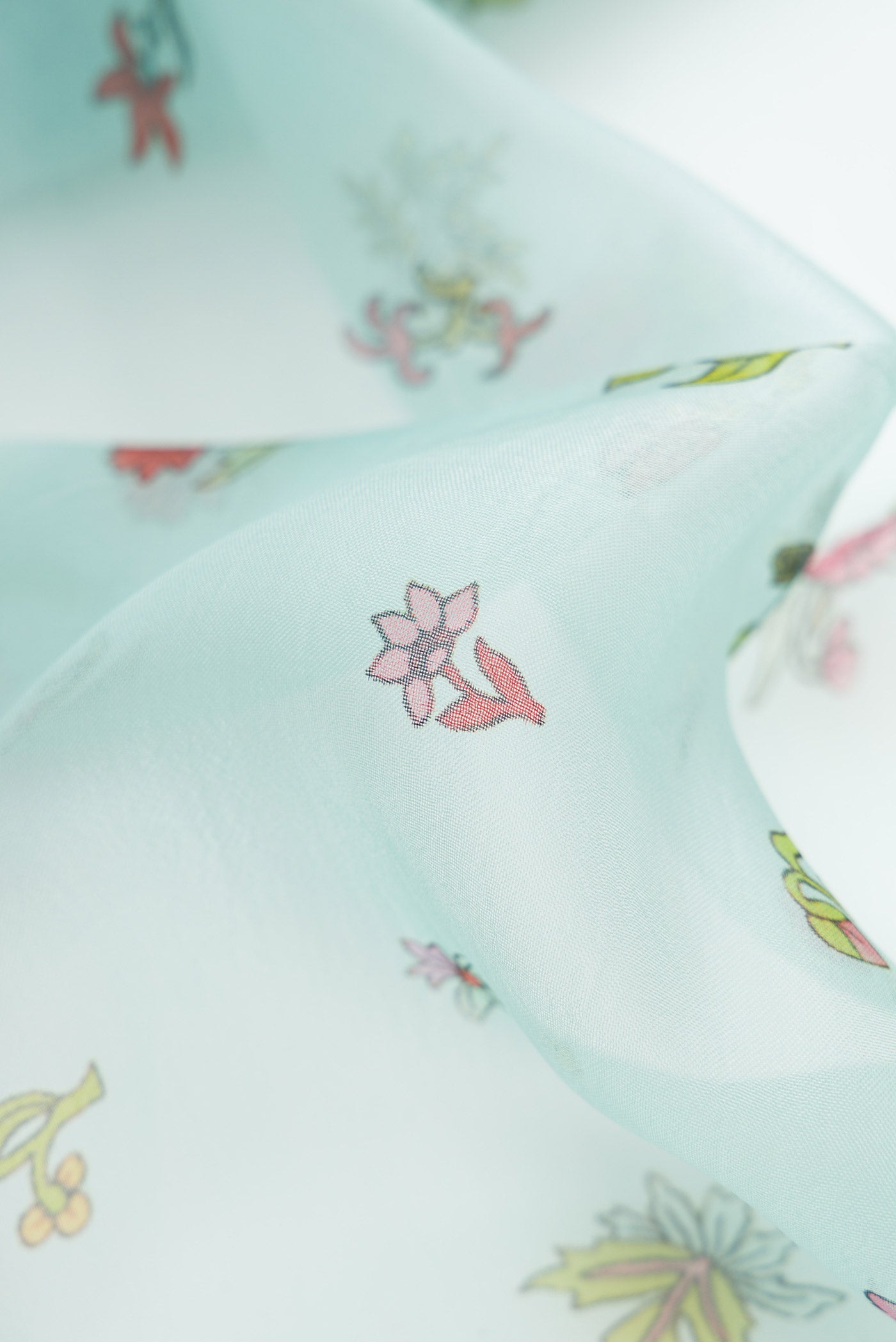 Close up of Light Blue Dual Tone Organza Silk Saree with Printed design on the body and Embroidery Border.  displaying folds