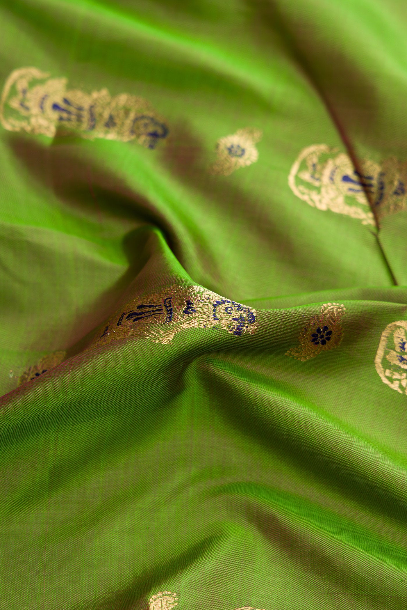 Close up of Green Dual Tone Baluchari Silk Saree with Zari And Thread Butta on the body and Zari Border.  displaying folds