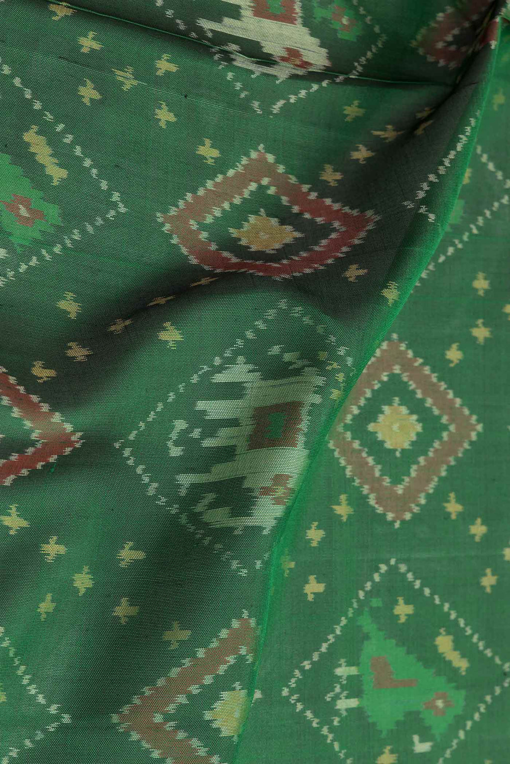 Close up of Green Dual Tone Double Ikat Saree with Ikat Print on the body and Zari And Thread Border.  displaying folds
