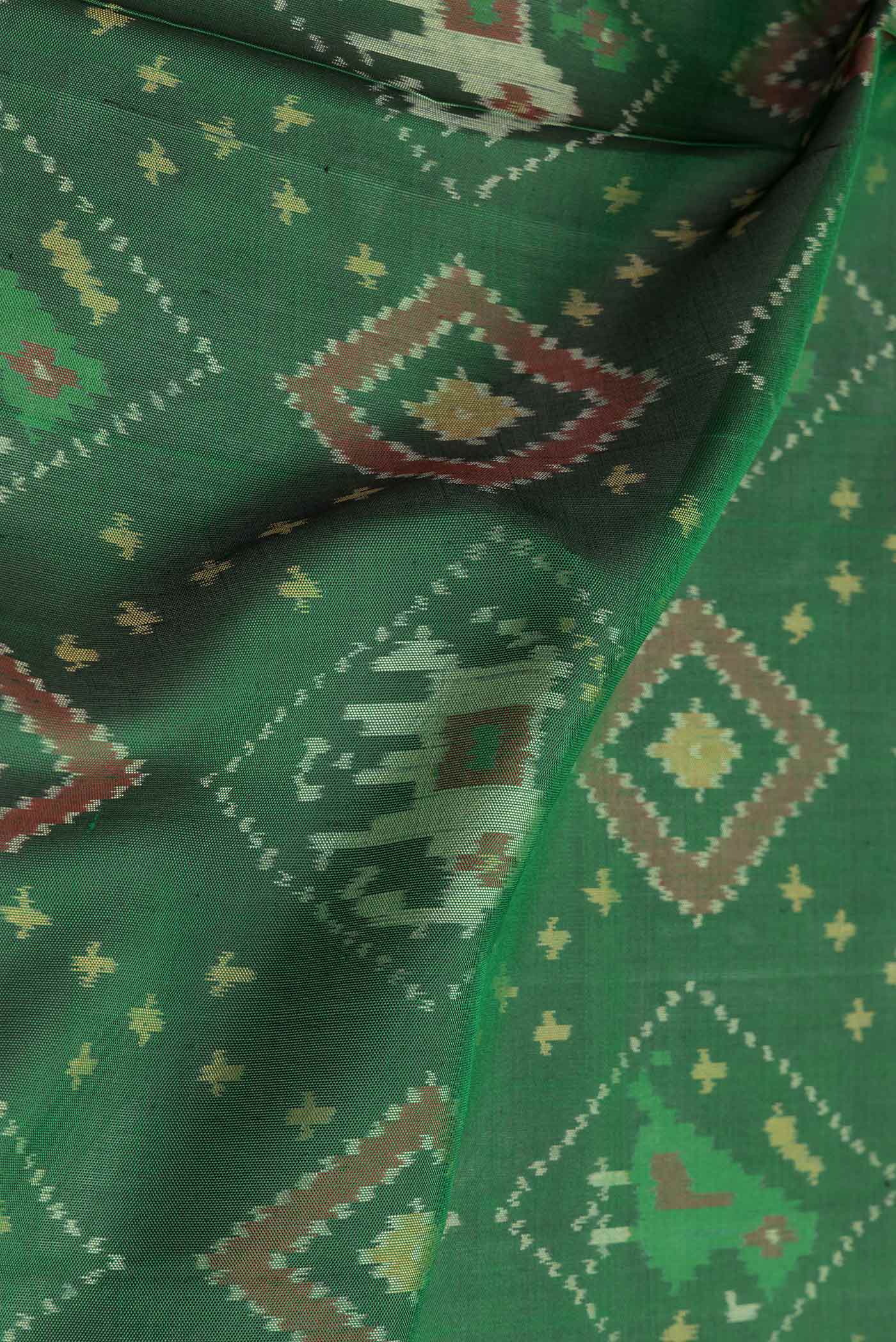 Close up of Green Dual Tone Double Ikat Saree with Ikat Print on the body and Zari And Thread Border.  displaying folds