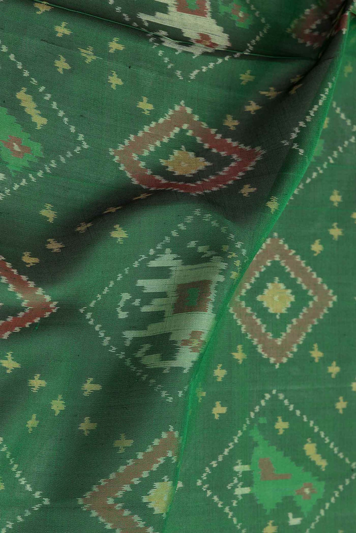 Close up of Green Dual Tone Double Ikat Saree with Ikat Print on the body and Zari And Thread Border.  displaying folds