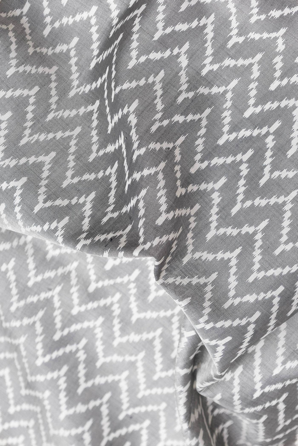 Close up of Grey Dual Tone Double Ikat Saree with Ikat Print on the body and Zari Border.  displaying folds