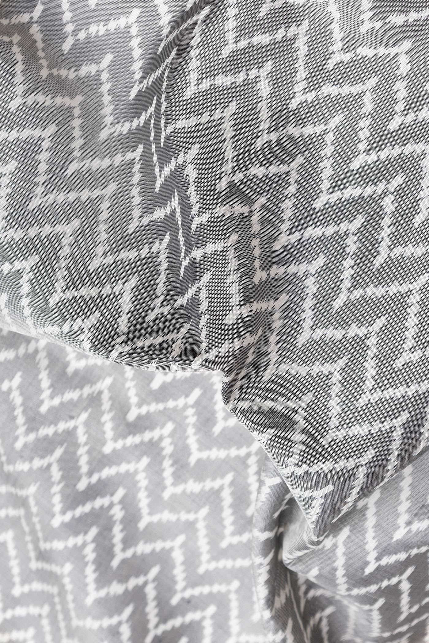 Close up of Grey Dual Tone Double Ikat Saree with Ikat Print on the body and Zari Border.  displaying folds