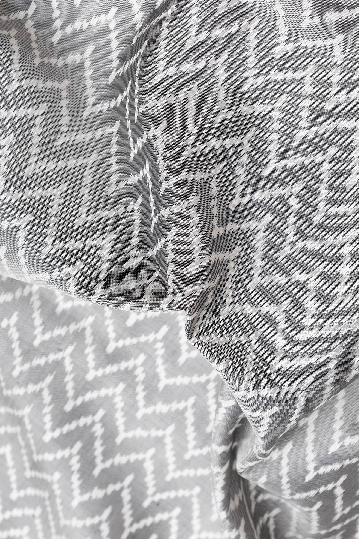 Close up of Grey Dual Tone Double Ikat Saree with Ikat Print on the body and Zari Border.  displaying folds