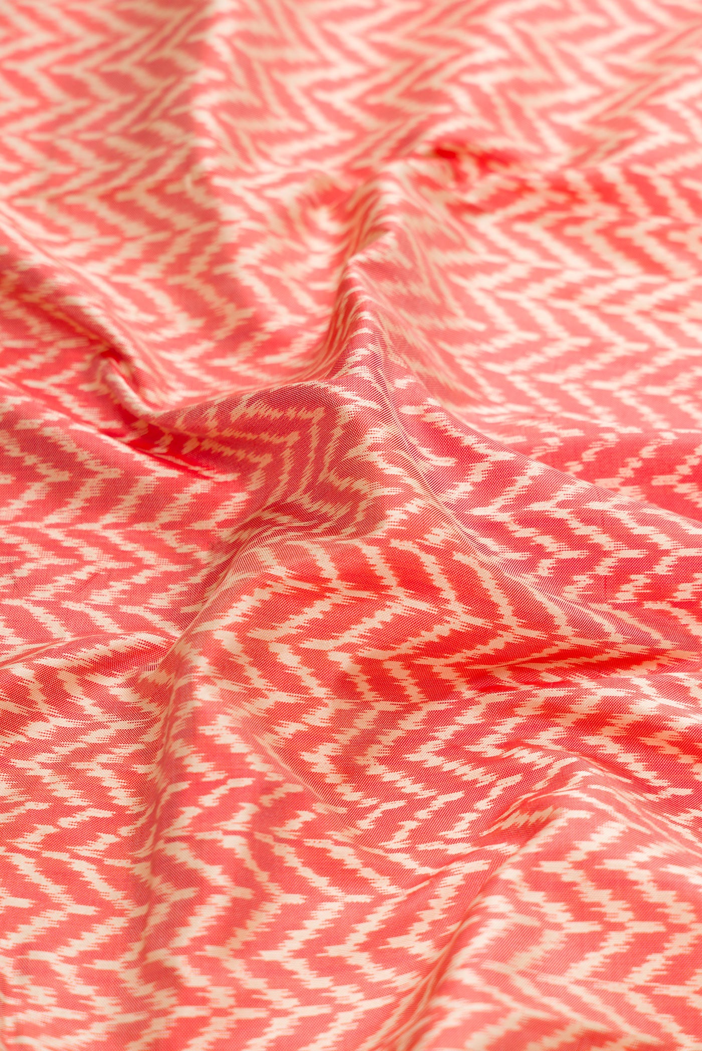 Close up of Orange Dual Tone Double Ikat Saree with Ikat Print on the body and Ikat Border.  displaying folds