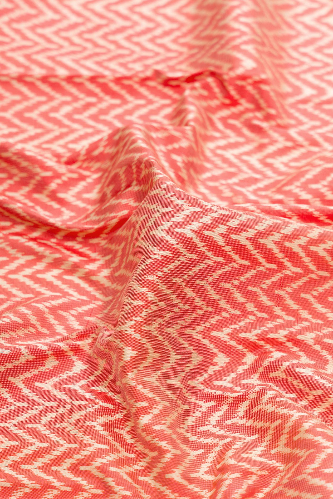 Close up of Off White and Orange Color Double Ikat Saree with Ikat Print on the body and Zari Border.  displaying folds