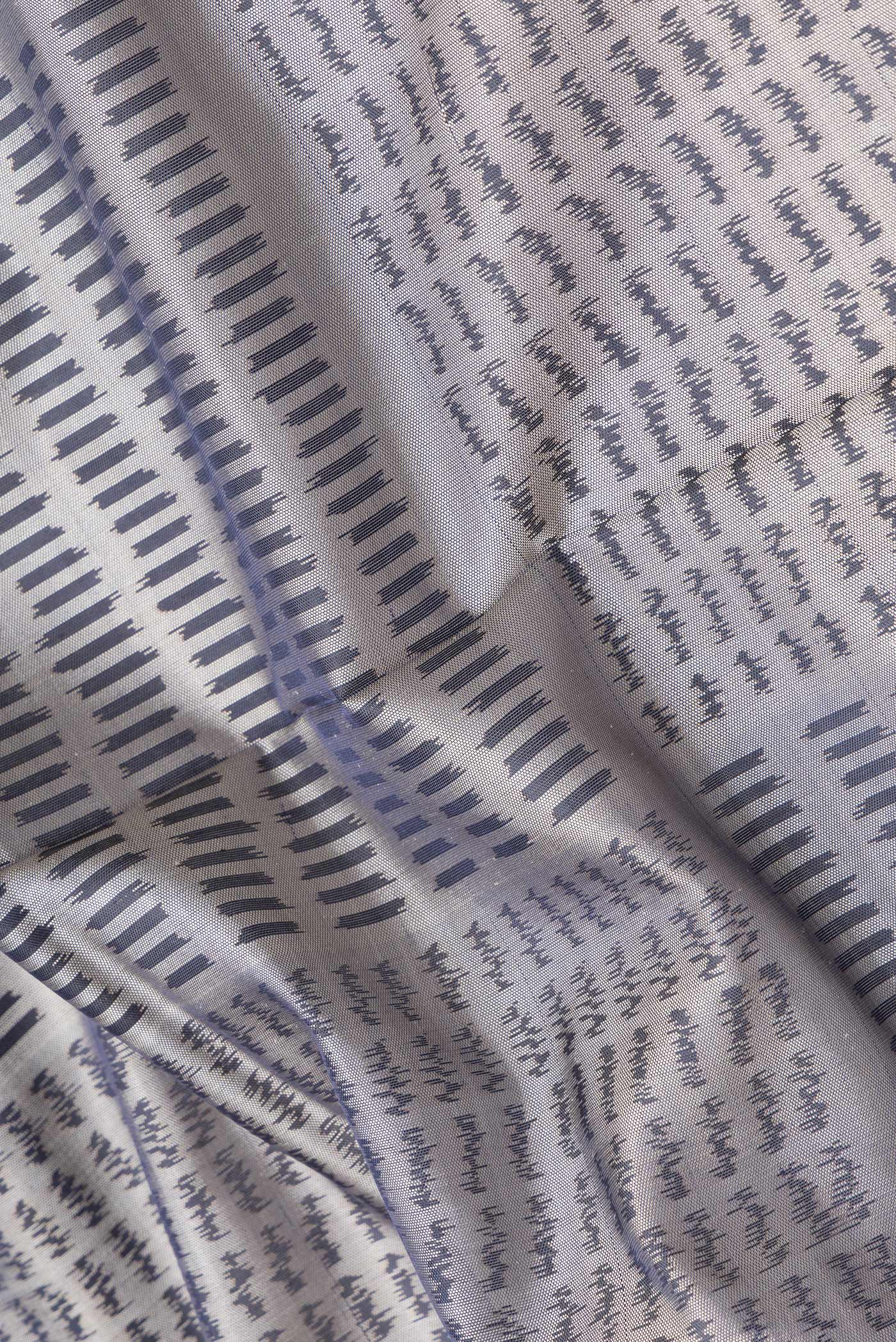 Close up of Grey Dual Tone Rajkot Patola Silk Saree with Ikat Print on the body and Zari Border.  displaying folds