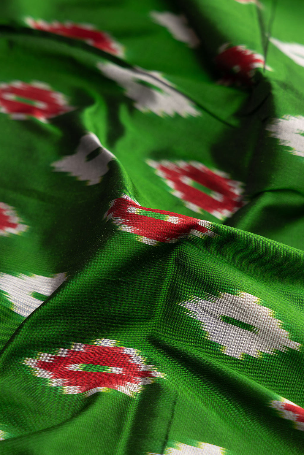 Close up of Parrot Green Dual Tone Double Ikat Saree with Ikat Print on the body and Zari Border.  displaying folds