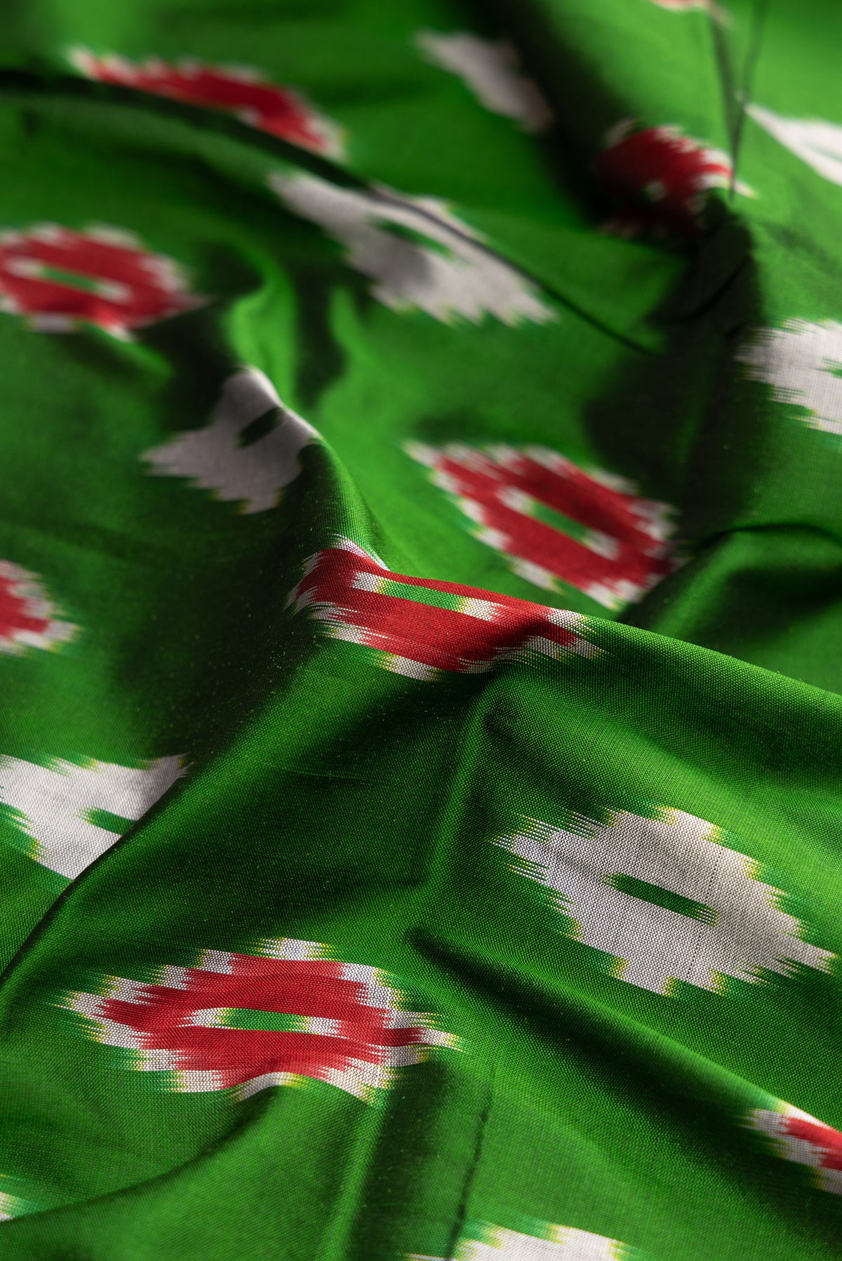 Close up of Parrot Green Dual Tone Double Ikat Saree with Ikat Print on the body and Zari Border.  displaying folds