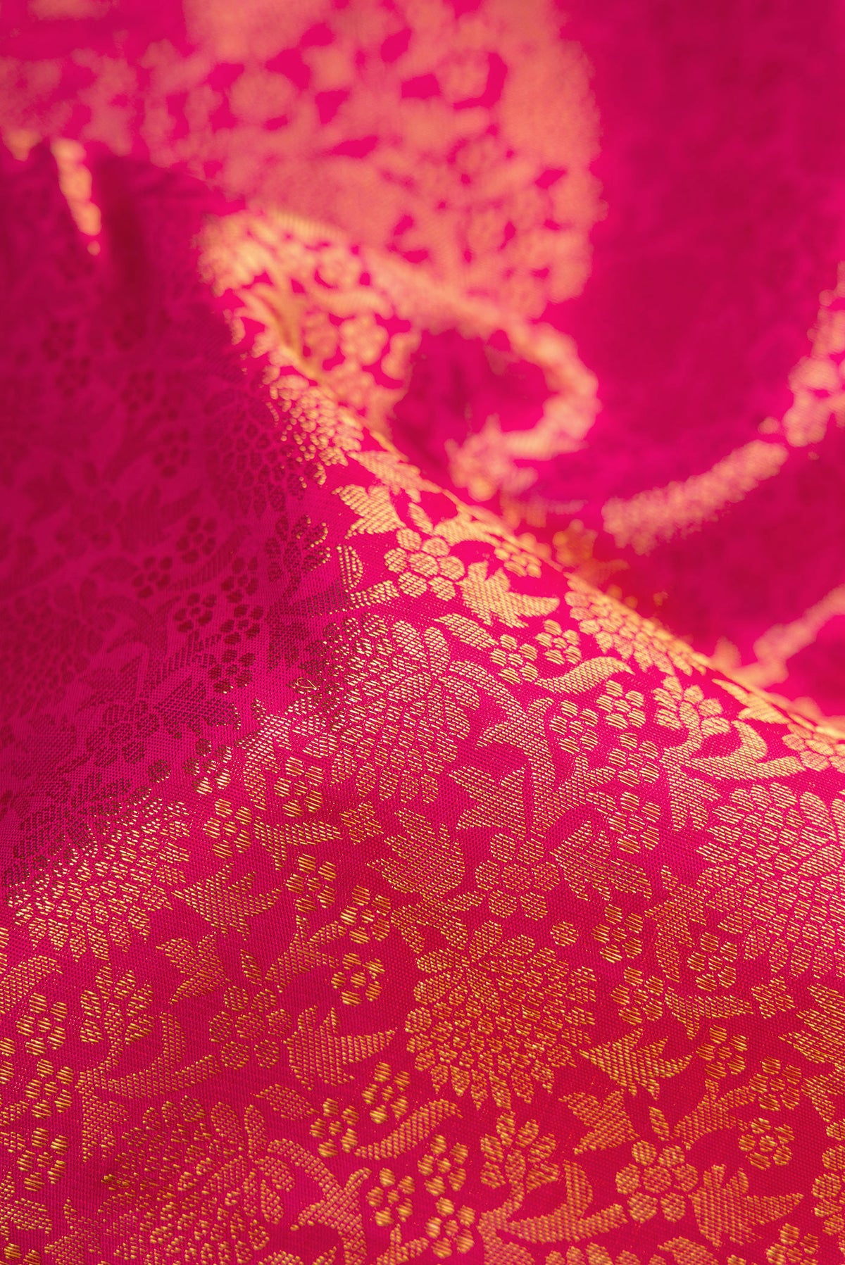 Close up of Pure Silk Pure Zari Magenta Dual Tone Kanjivaram Saree with Zari Brocade on the body and Zari Border.  displaying folds