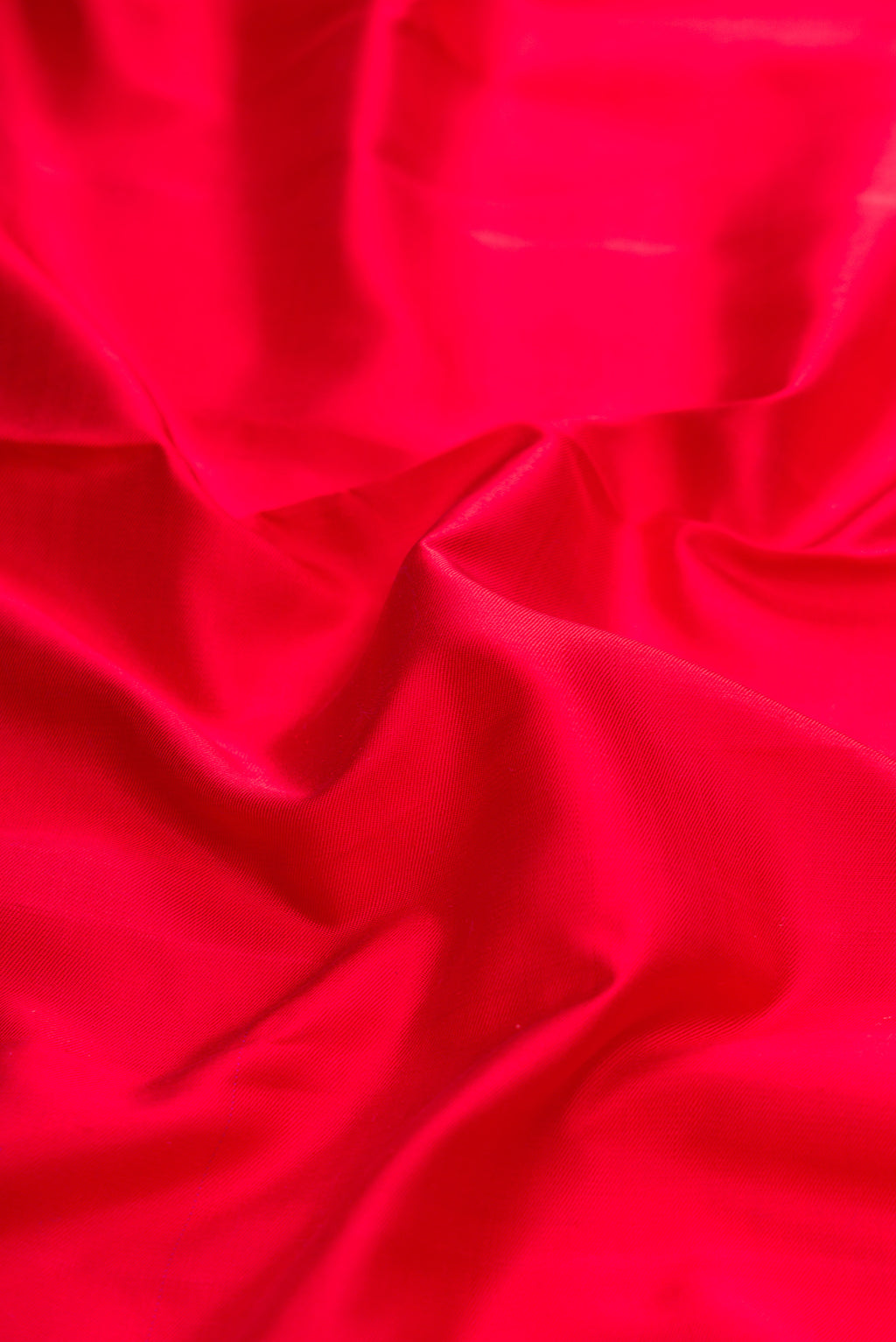 Close up of Red Dual Tone Double Ikat Saree with Plain Body and Zari Border.  displaying folds