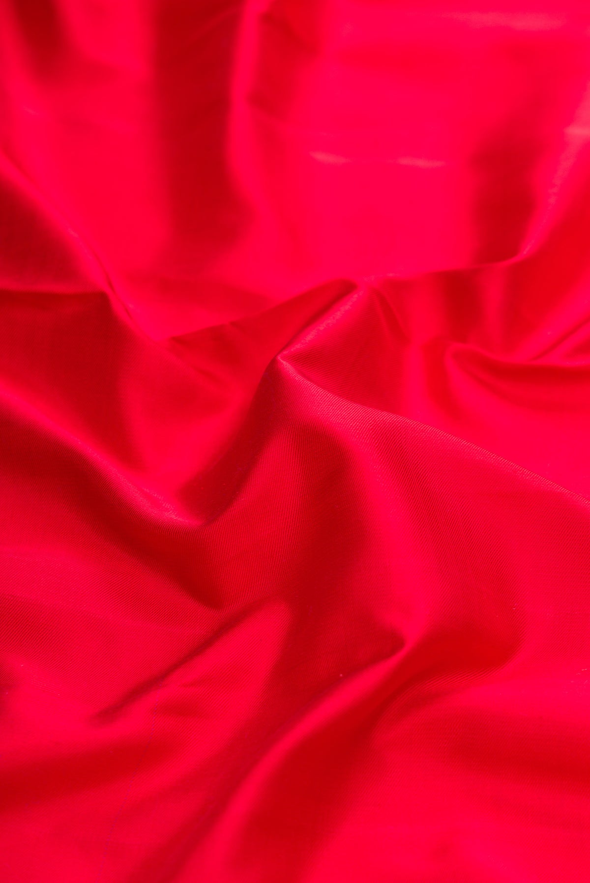 Close up of Red Dual Tone Double Ikat Saree with Plain Body and Zari Border.  displaying folds