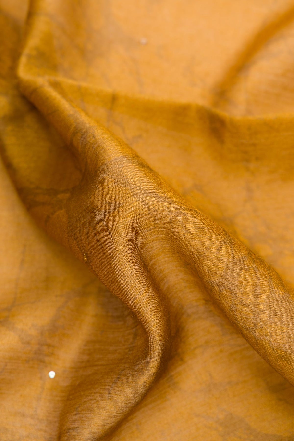 Close up of Mustard Dual Tone Tussar Silk Saree with Printed design on the body and Zari Border.  displaying folds