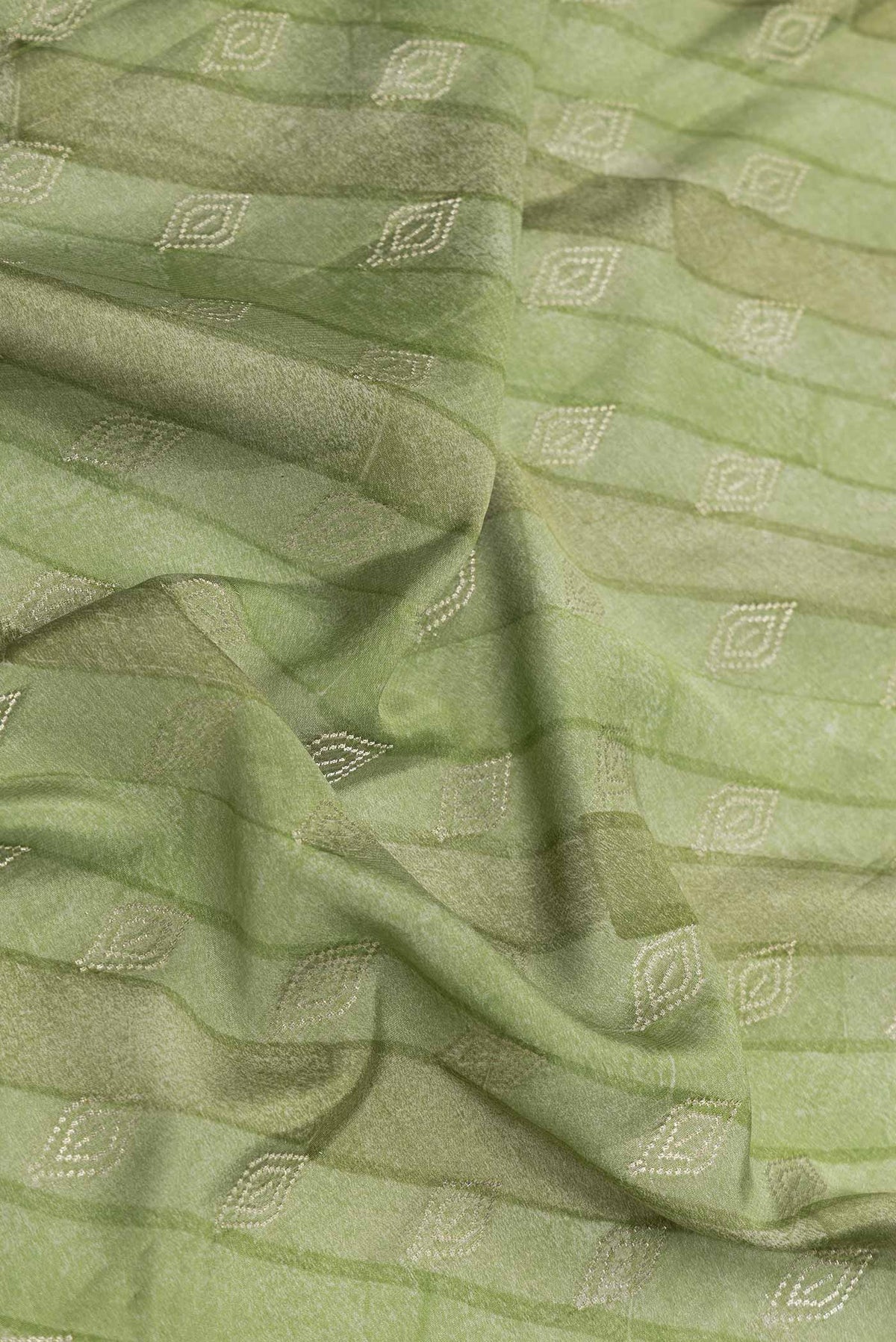 Close up of Green Dual Tone Mysore Georgette Saree With Printed design on the body and Zari Border displaying folds