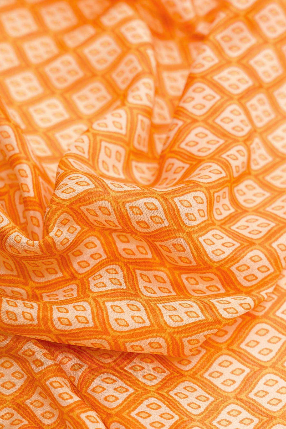 Close up of Orange Dual Tone Mysore Crepe Saree with Printed design on the body and Zari Border.  displaying folds