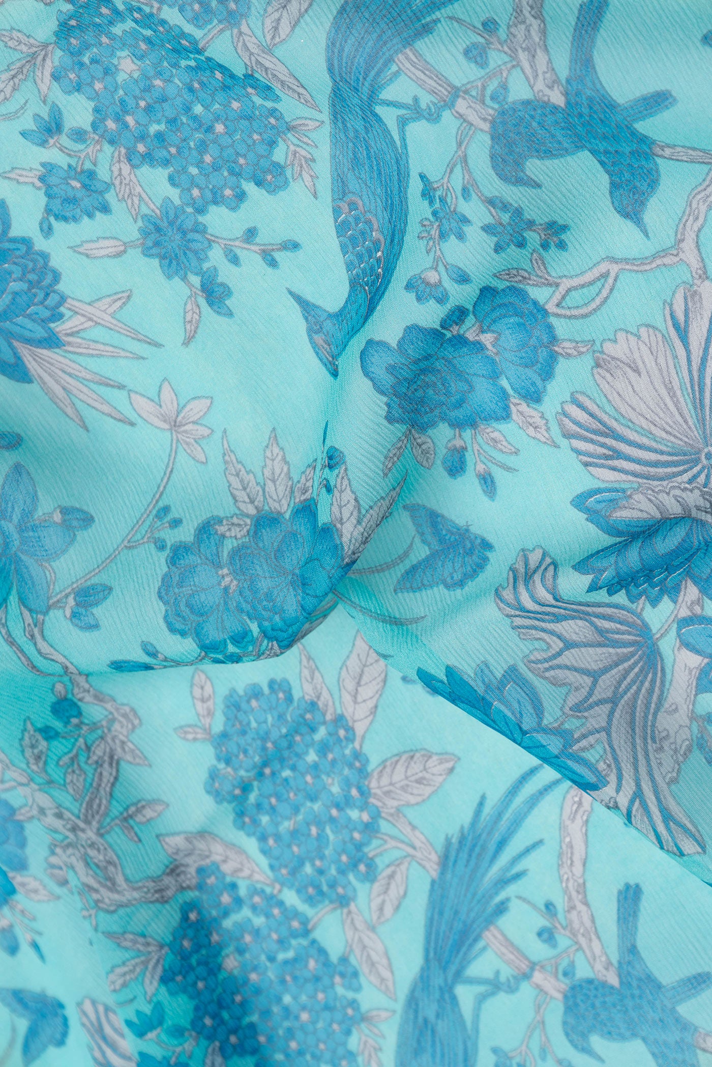 Close up of Sky Blue Mysore Chiffon Saree with Printed design on the body and Zari And Thread Border.  displaying folds