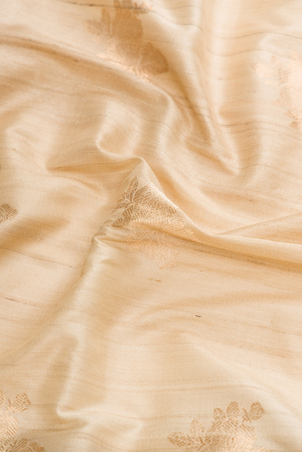 Close up of Beige Dual Tone Tussar Silk Saree with Zari Butta on the body and Zari And Thread Border.  displaying folds