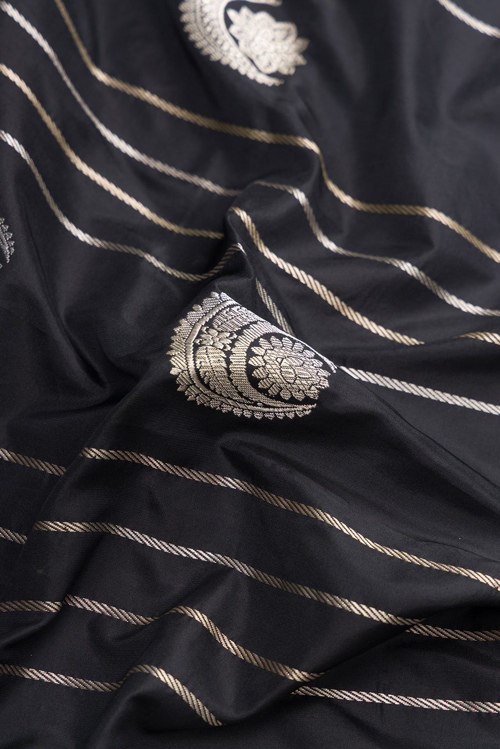 Close up of Black Dual Tone Banarasi Silk Saree with Zari Butta on the body and Zari Border.  displaying folds