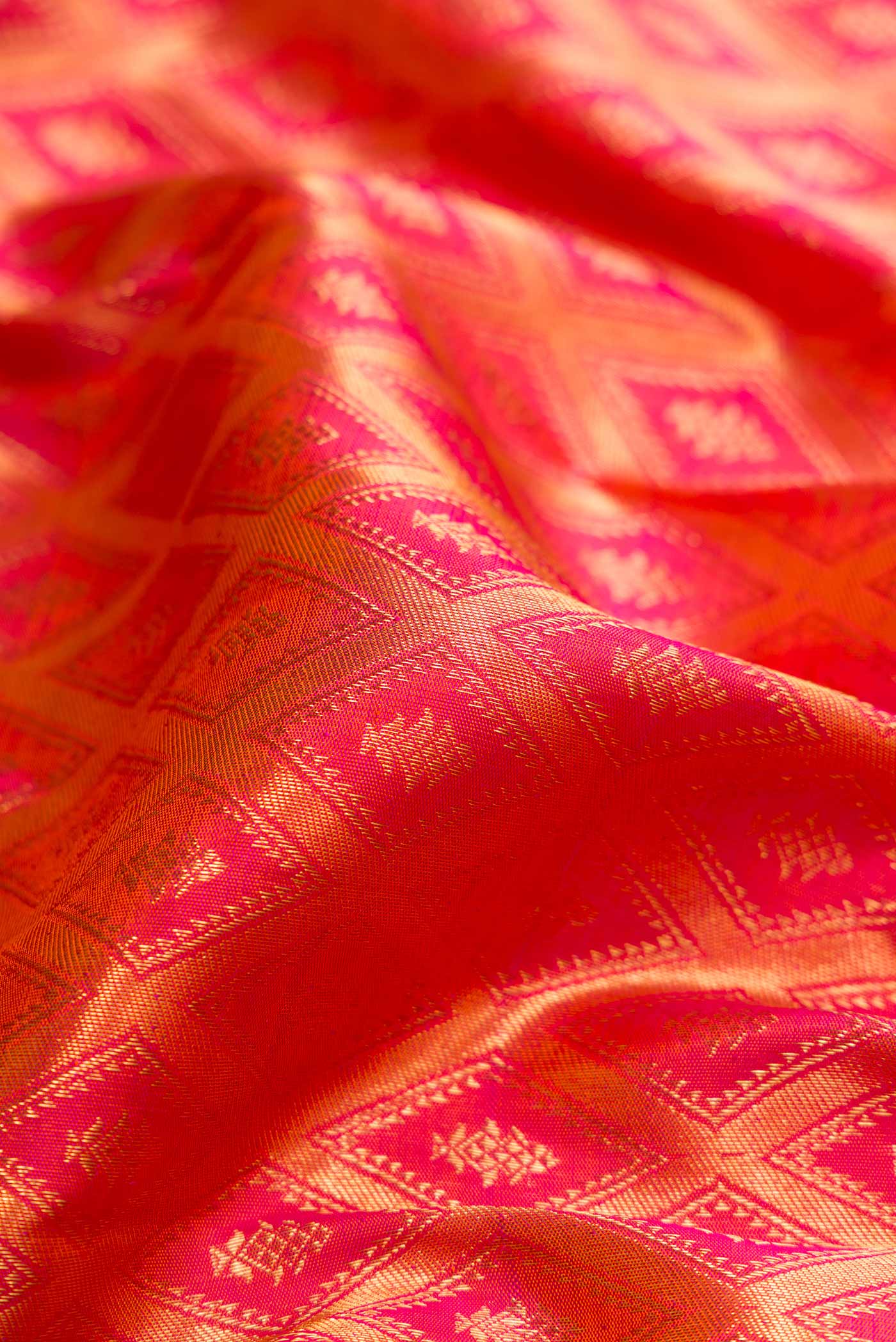 Close up of Brick Orange Dual Tone Kanchipuram Silk Saree with Zari Brocade on the body and Zari Border displaying folds