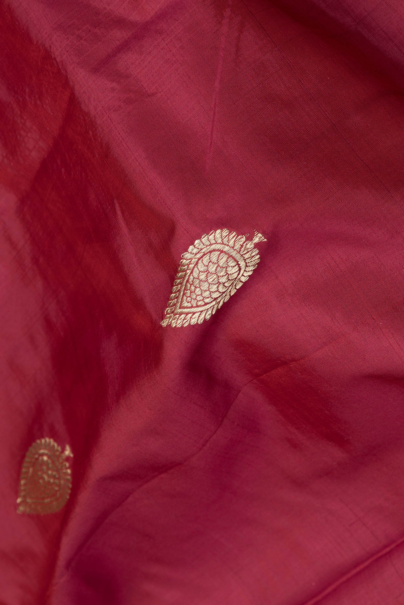 Close up of Maroon Dual Tone Banarasi Silk Saree with Zari Butta on the body and Zari Border.  displaying folds