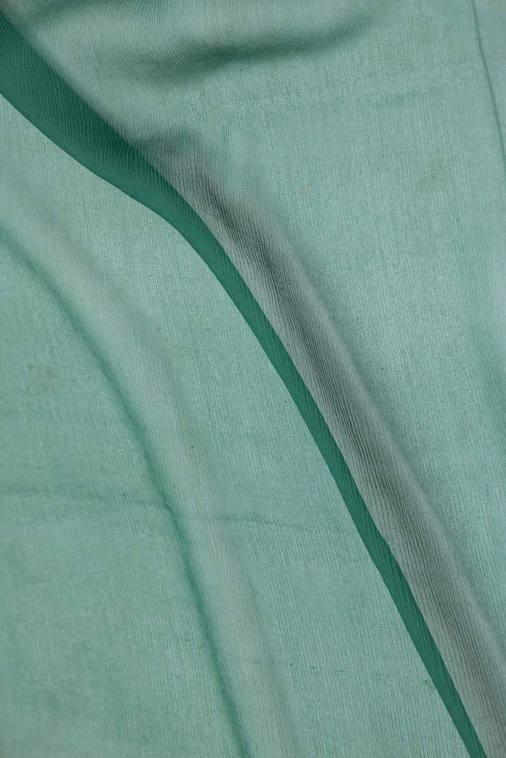 Close up of Bottle Green Dual Tone Chiffon Saree with Embroidery on the body and Zari Border displaying folds