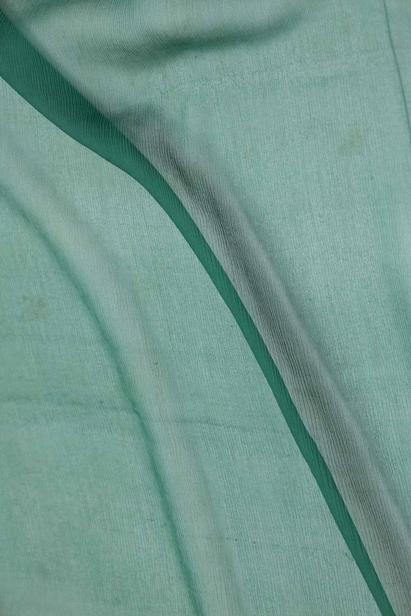 Close up of Bottle Green Dual Tone Chiffon Saree with Embroidery on the body and Zari Border displaying folds