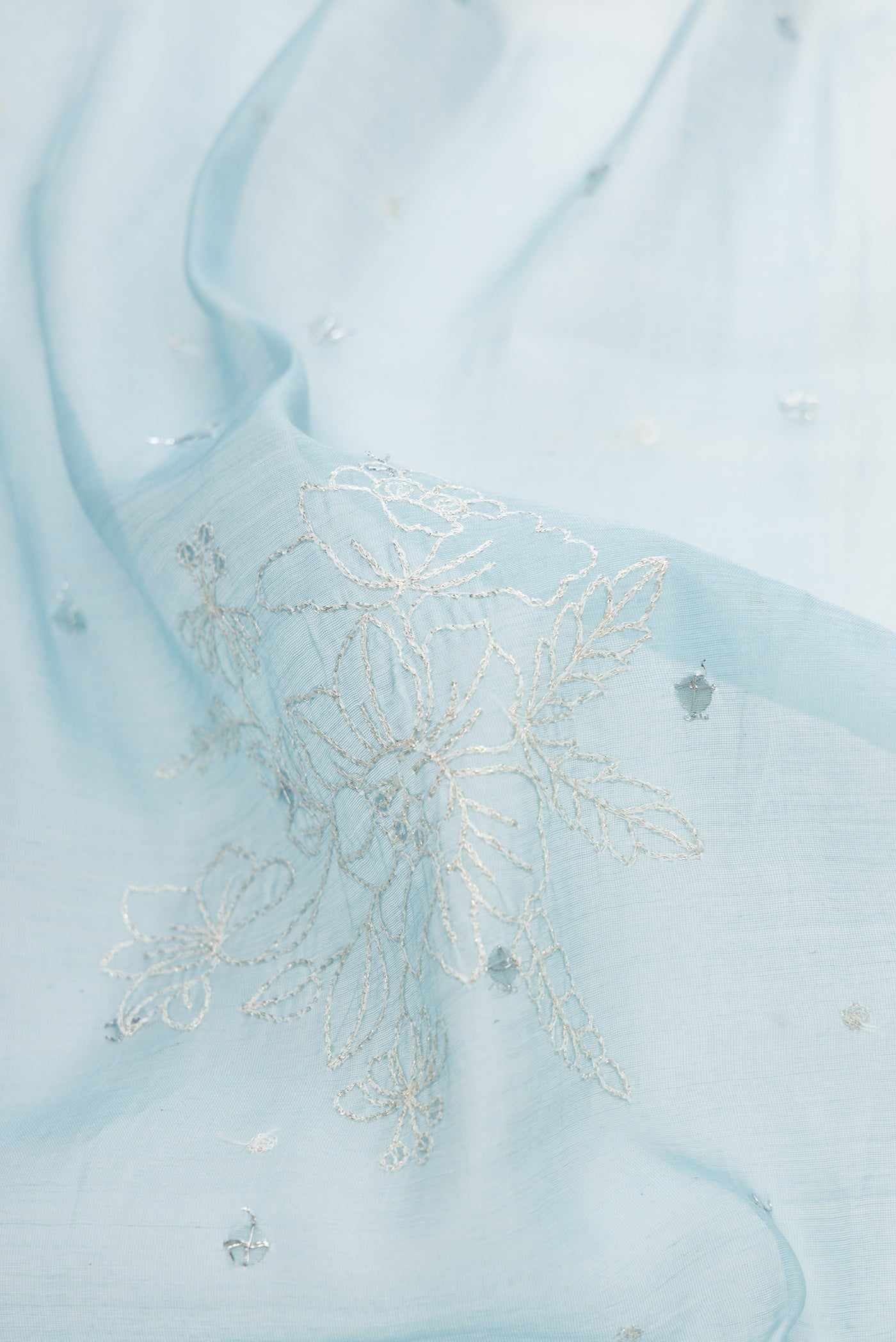 Close up of Light Blue Dual Tone Organza Silk Saree with Embroidery on the body and Plain Border.  displaying folds