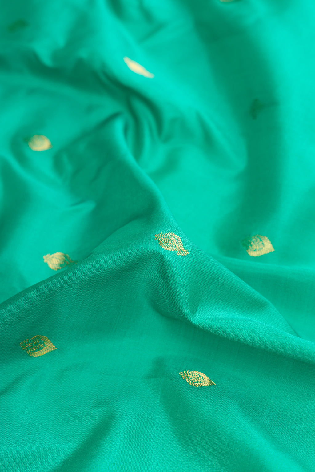 Close up of Sea Green Gadwal Silk Saree with Zari Butta on the body and Zari Border.  displaying folds