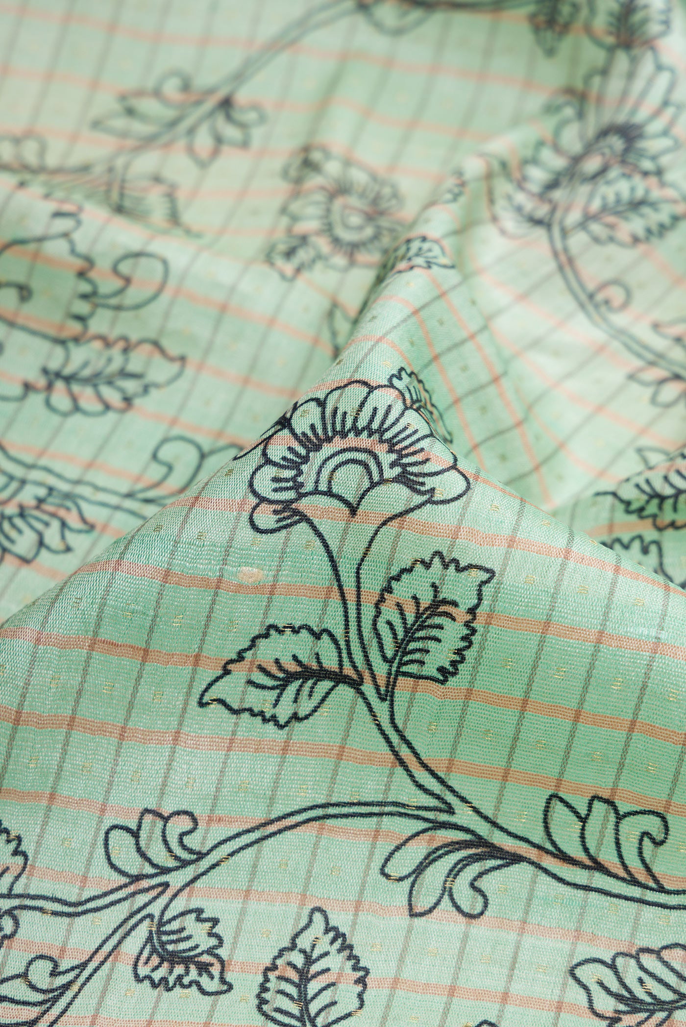 Close up of Sea Green Dual Tone Tussar Silk Saree with Printed design on the body and Fancy Border.  displaying folds