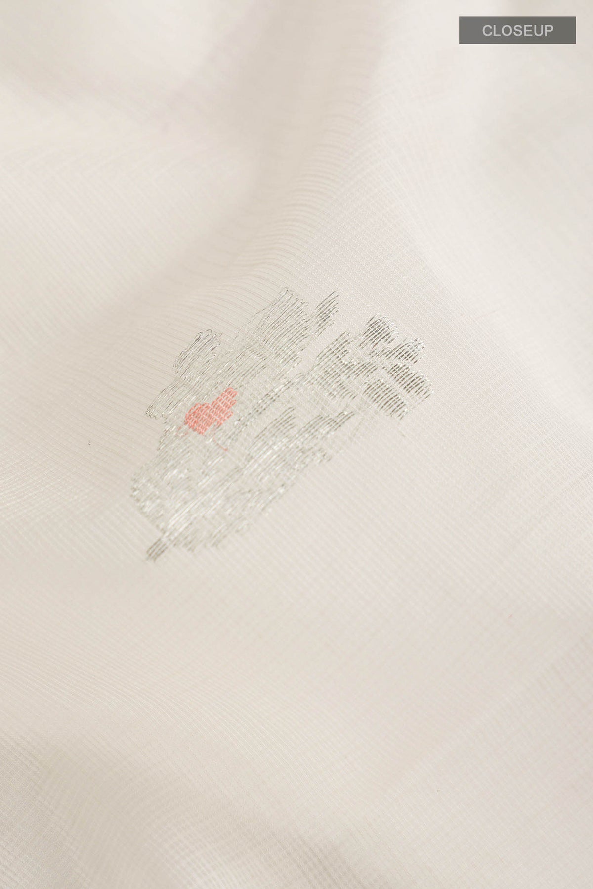 Close up of Peach Kota Silk Saree with Zari And Thread Butta on the body and Zari Border displaying folds