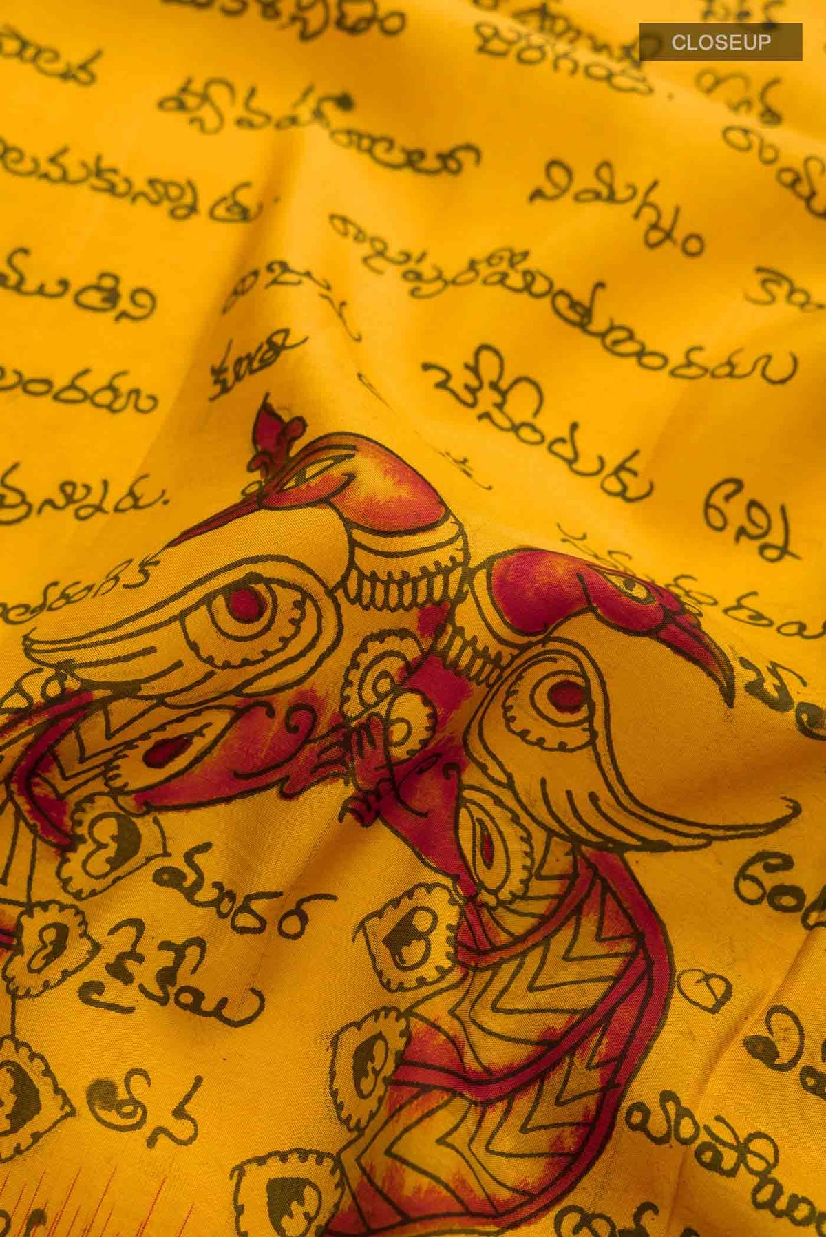 Close up of Mustard Kanchipuram Silk Saree with kalamkari Print on the body and Zari Border displaying folds